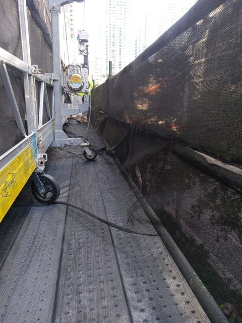 A person is standing on a scaffolding next to a fence.
