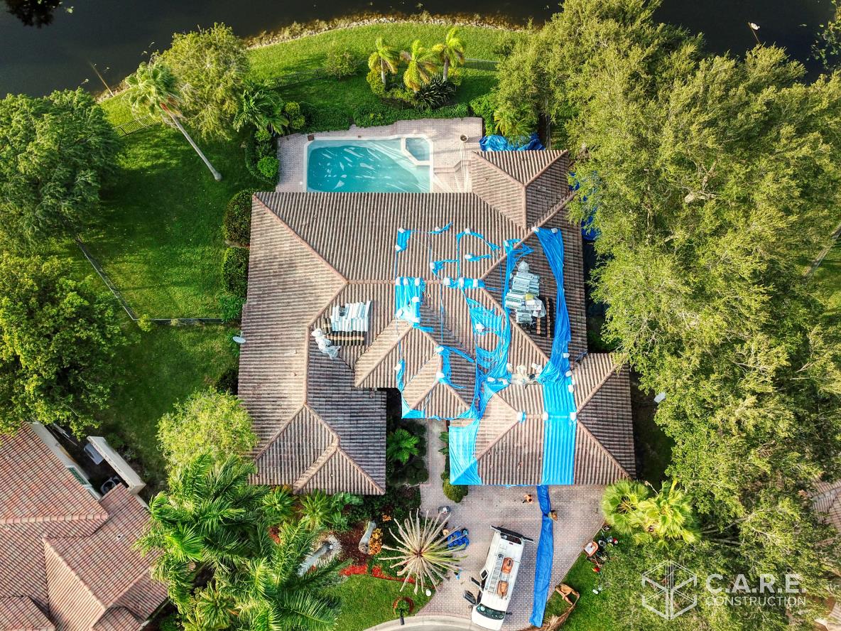An aerial view of a house with a pool surrounded by trees.
