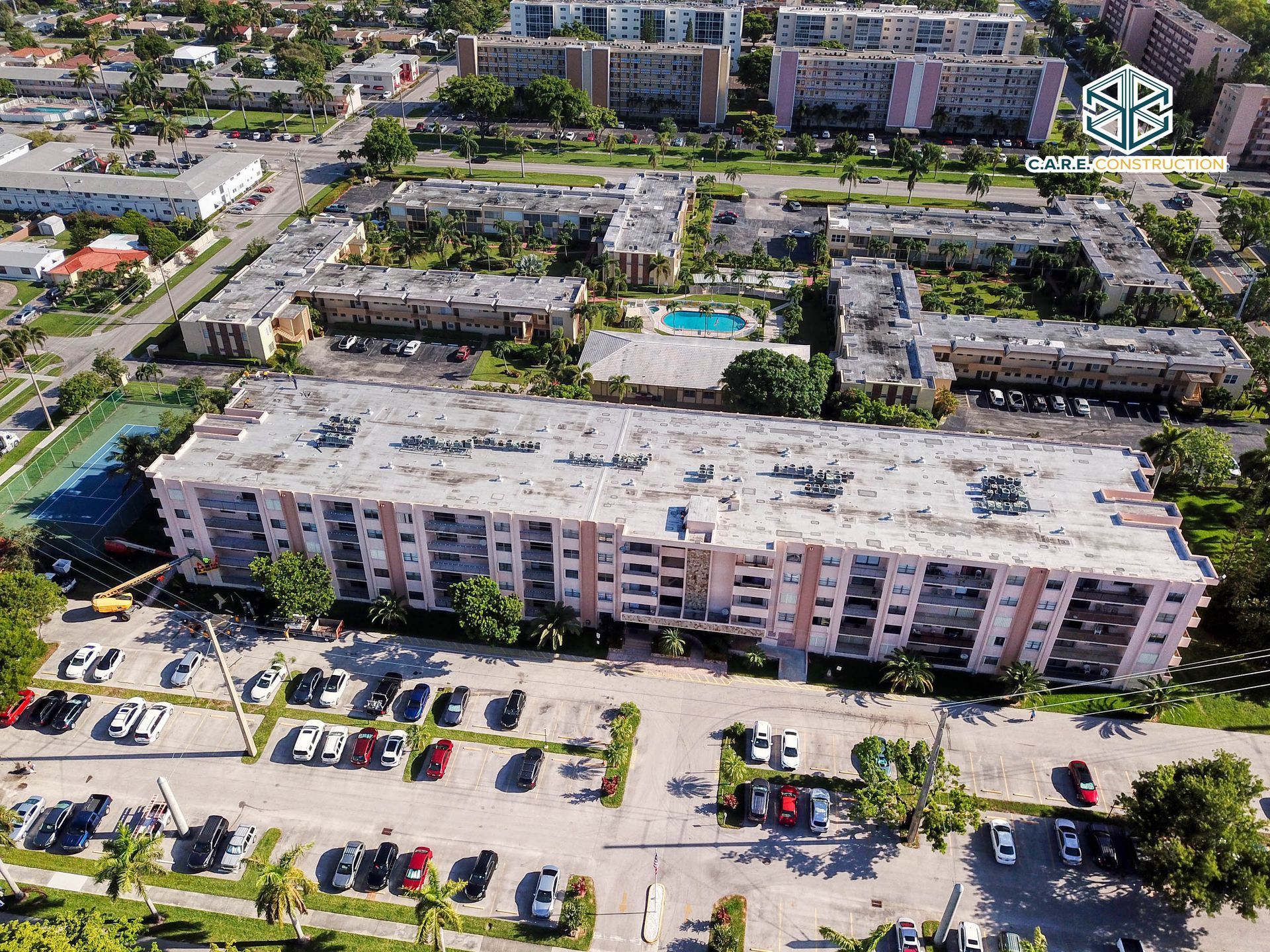 An aerial view of a large apartment building with a parking lot in front of it.