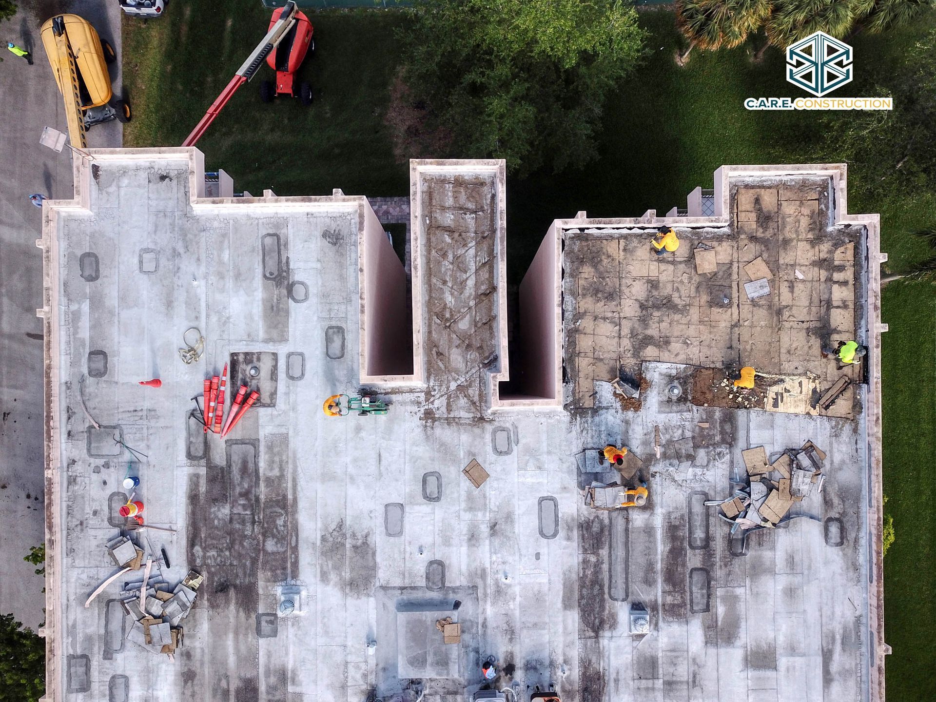 An aerial view of a building under construction with workers on the roof.