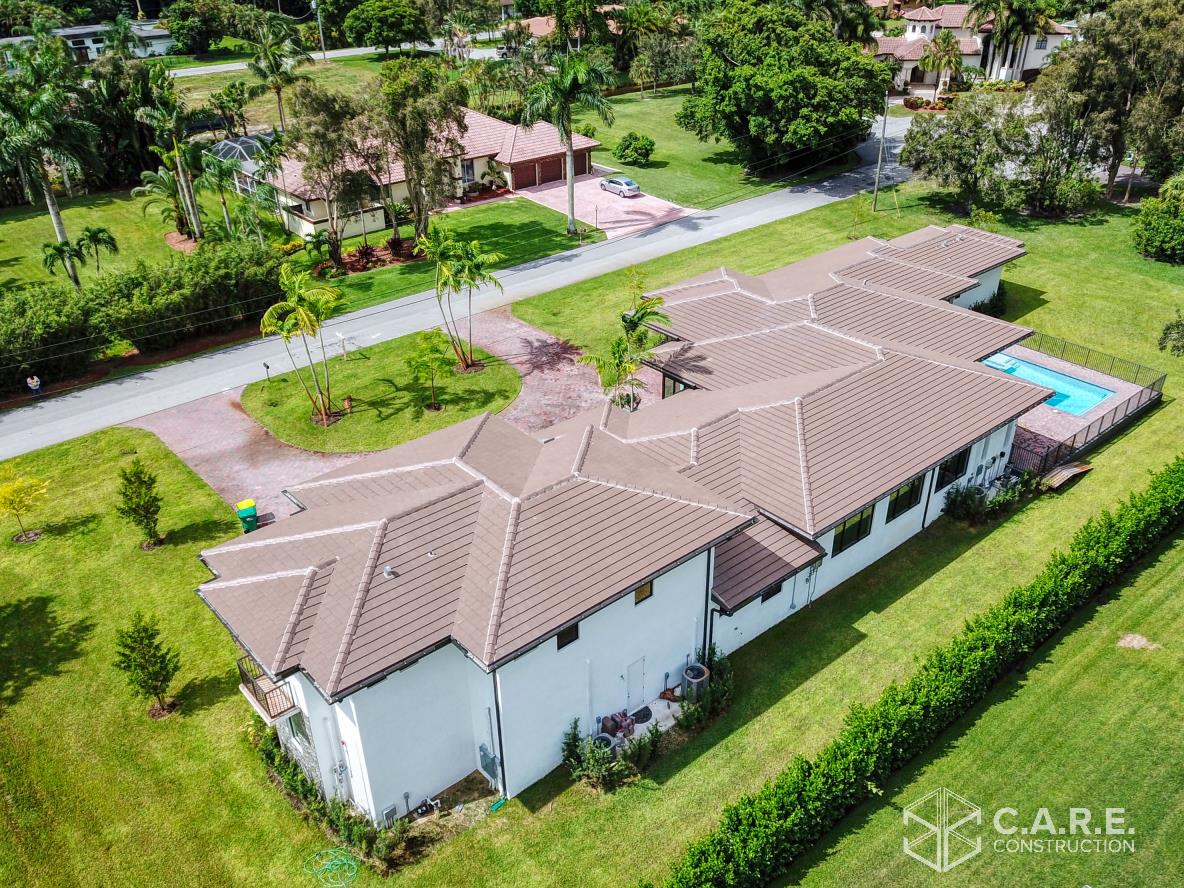 An aerial view of a house with a brown roof and a pool.