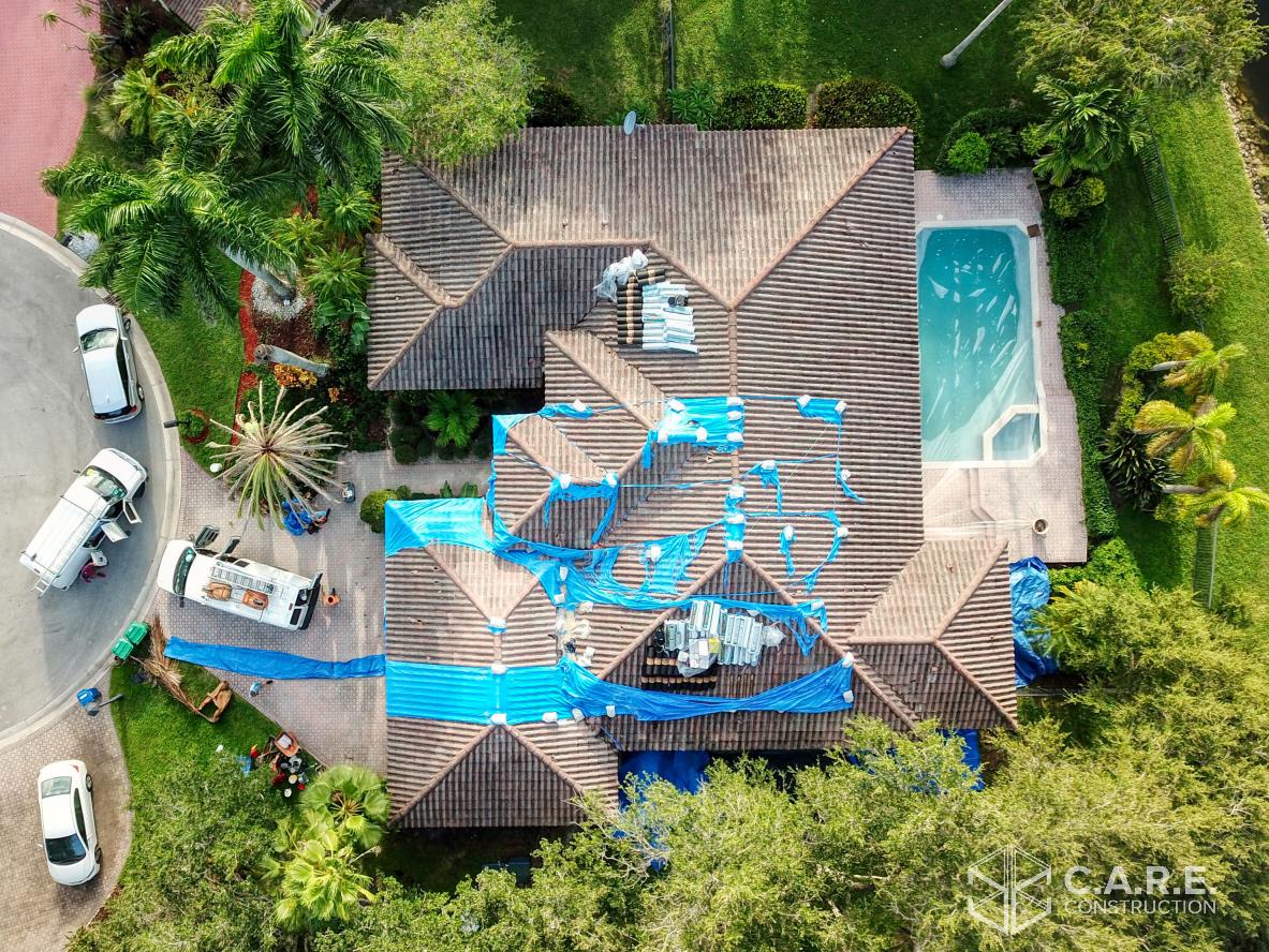 An aerial view of a house with a pool and a roof being painted.