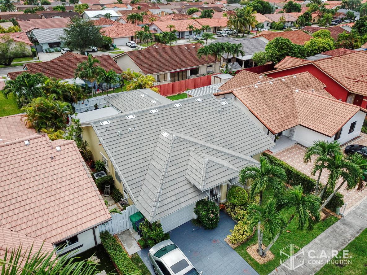An aerial view of a house in a residential area with a car parked in front of it.