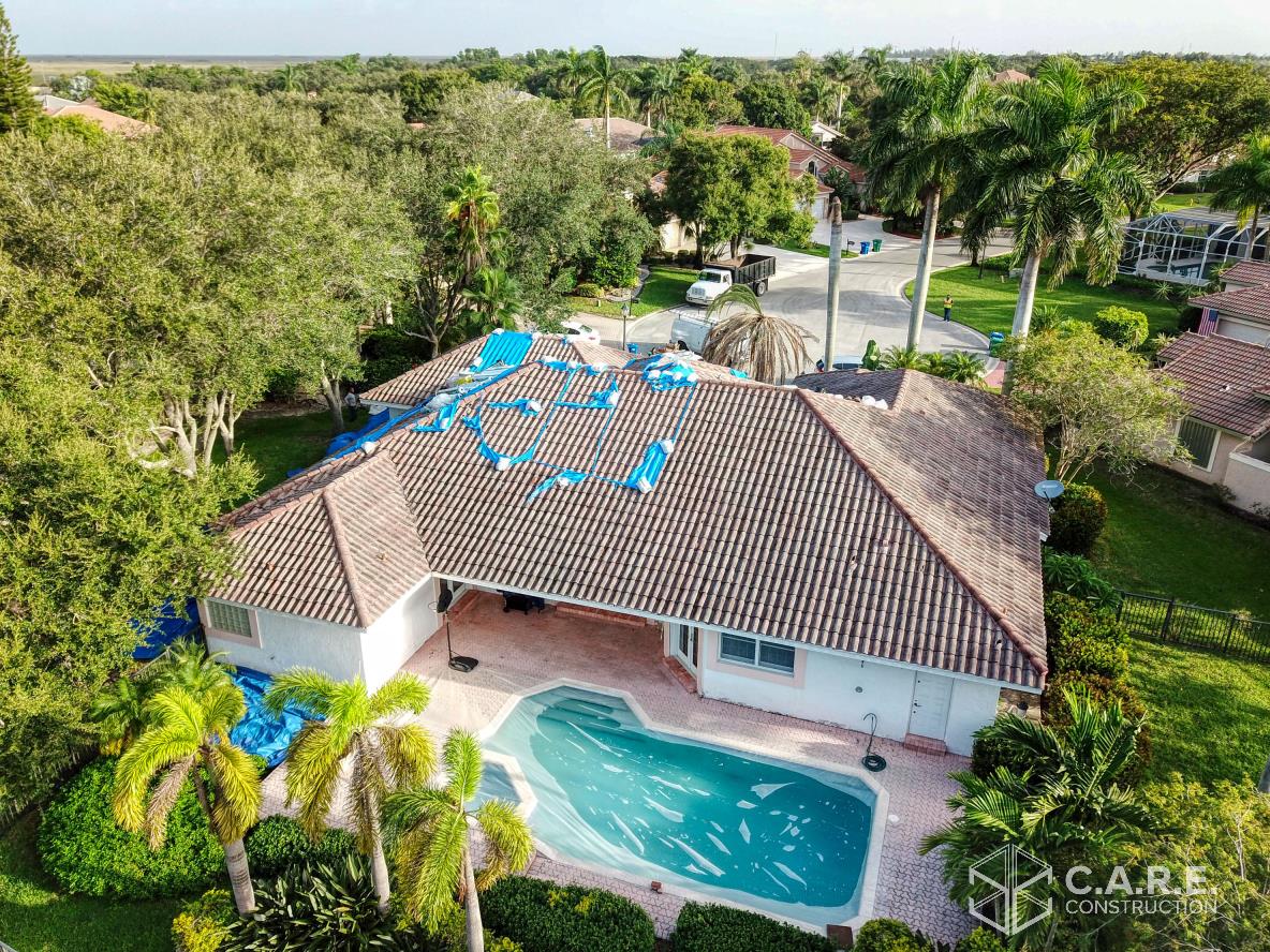 An aerial view of a house with a pool and a roof that is being repaired.