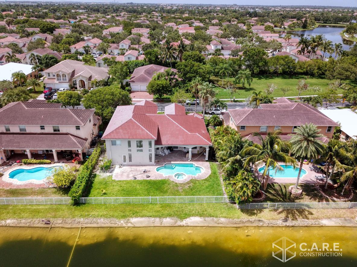 An aerial view of a house with two pools in a residential area.
