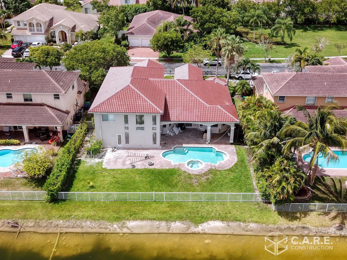 An aerial view of a house with a pool in a residential area.