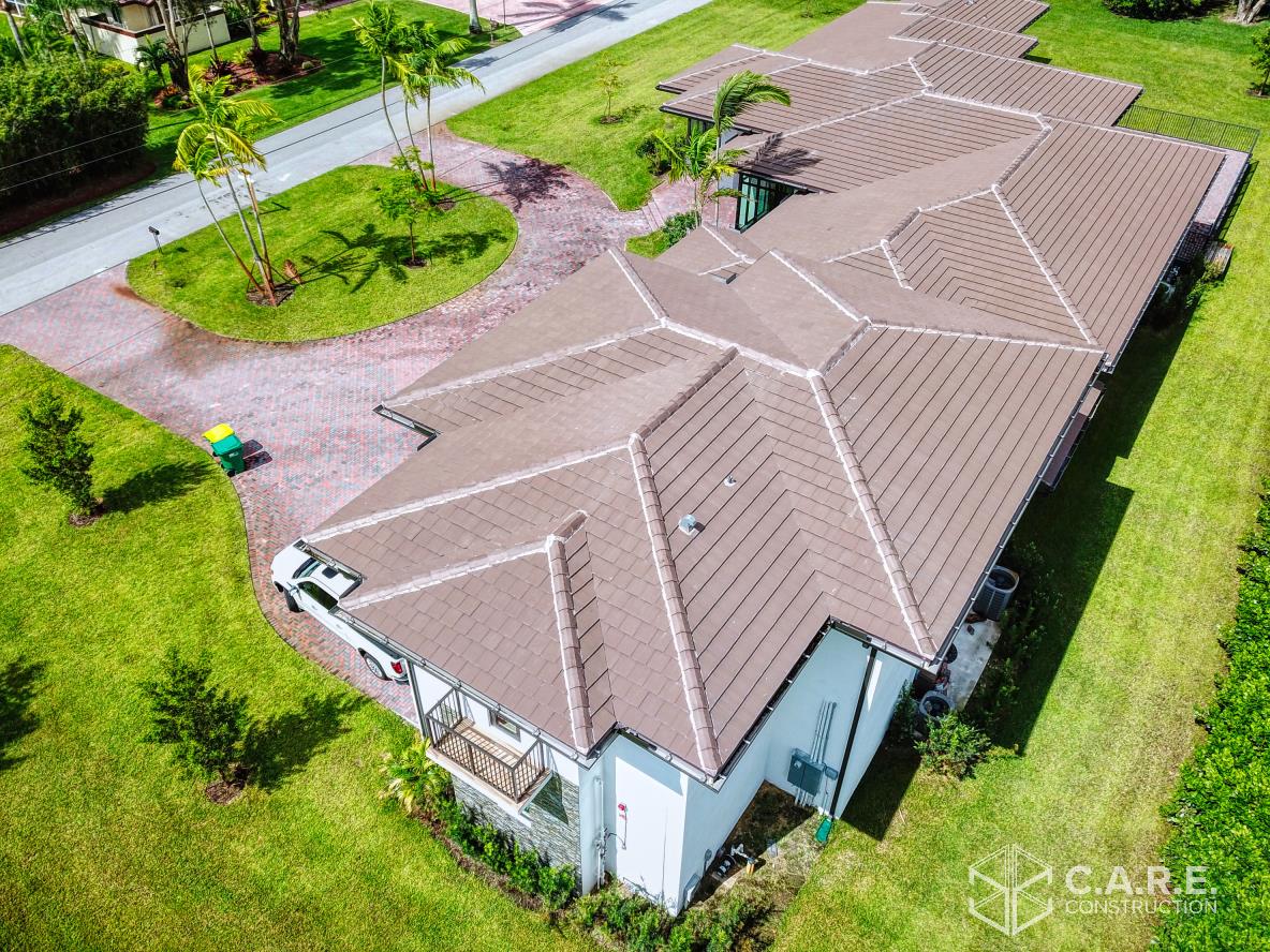 An aerial view of a house with a brown roof and a driveway.