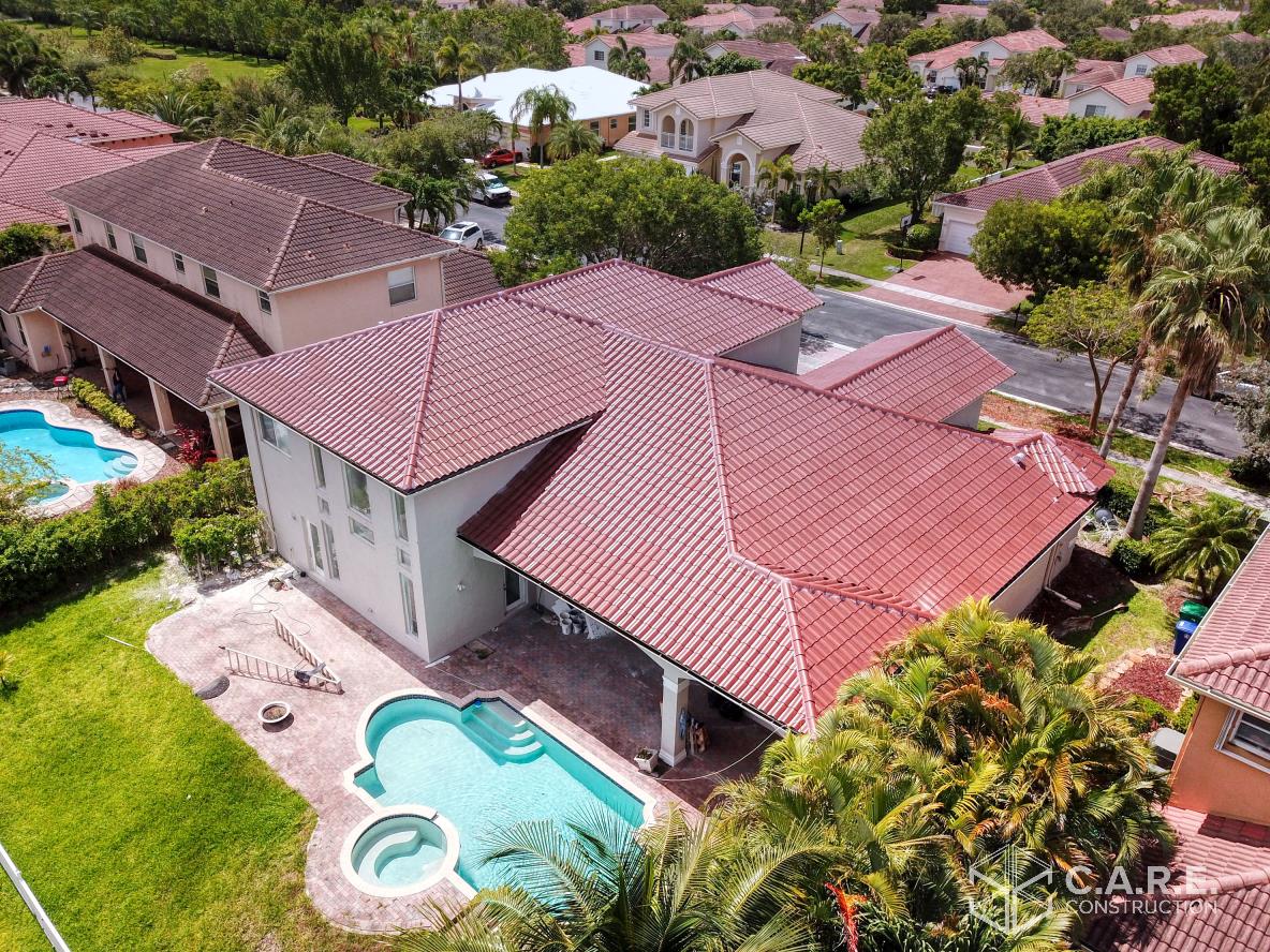 An aerial view of a house with a pool in a residential area.