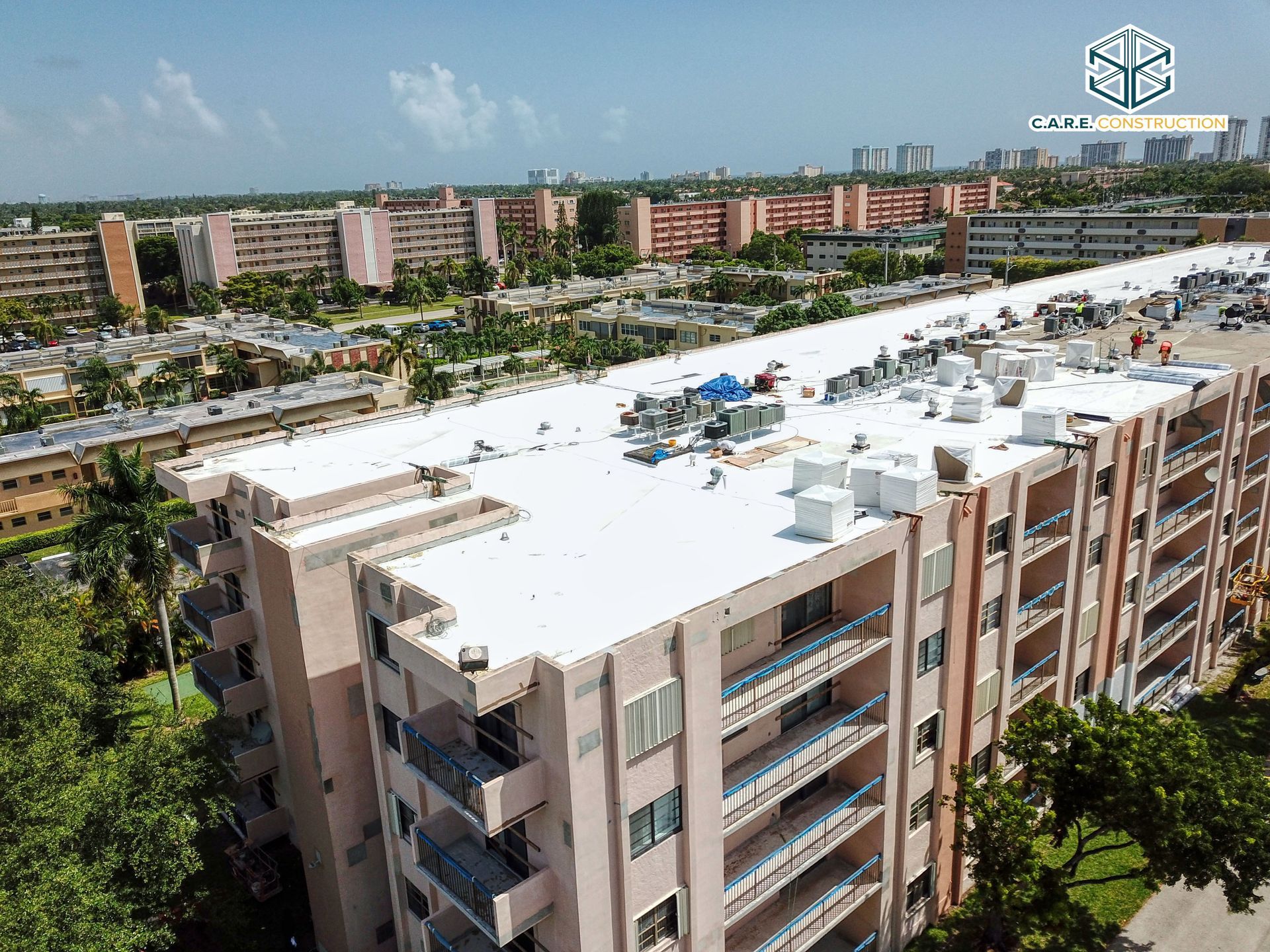 An aerial view of a large apartment building with a white roof.