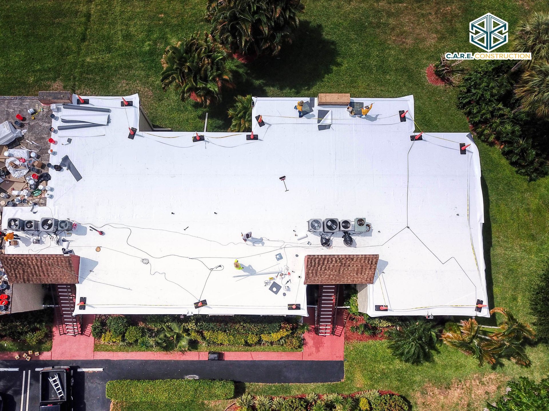 An aerial view of a building with a white roof being installed.