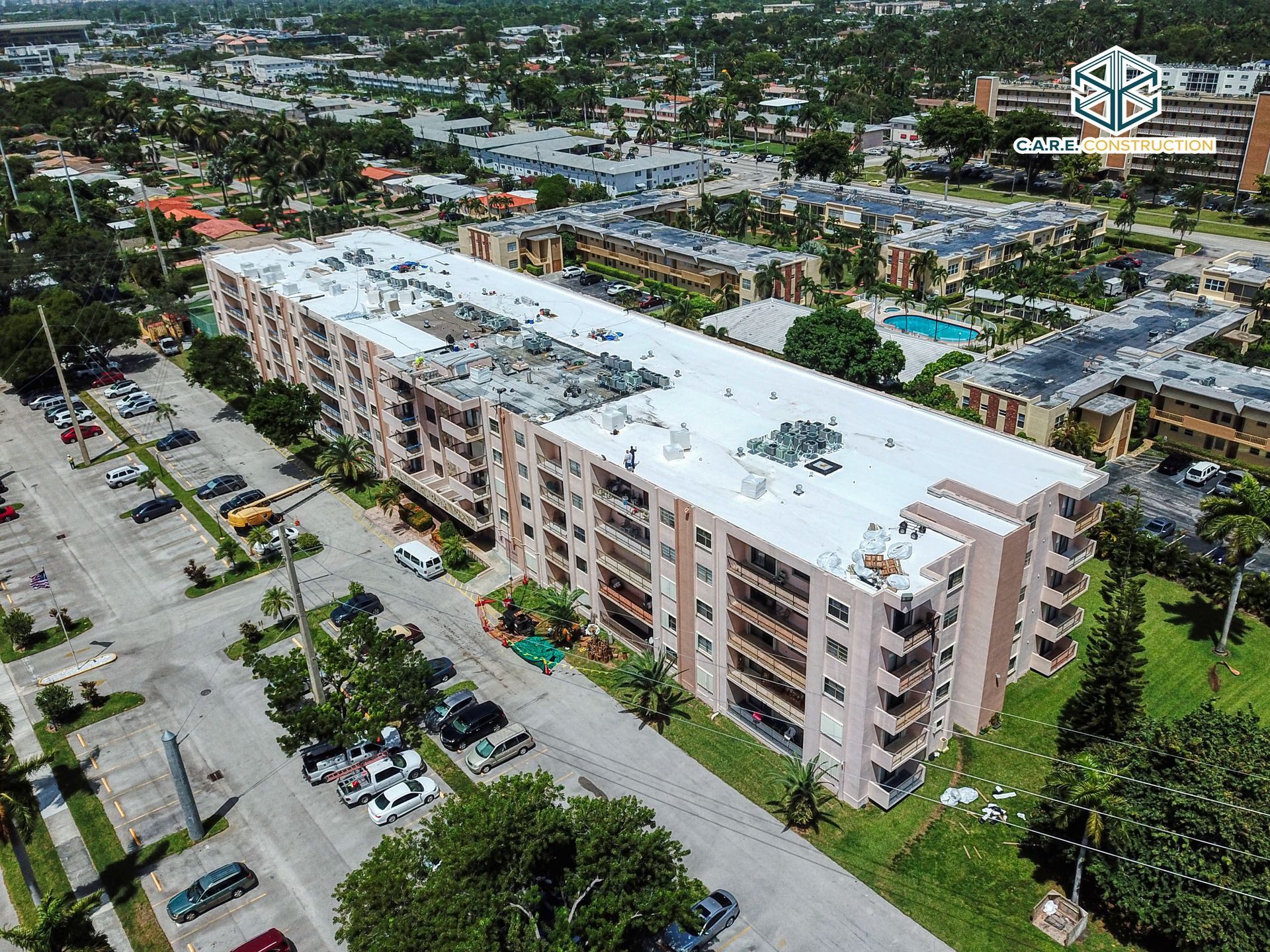 An aerial view of a large apartment building with a white roof in a city.
