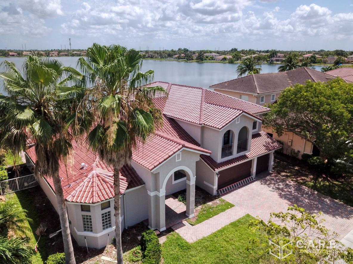 An aerial view of a large house with a lake in the background