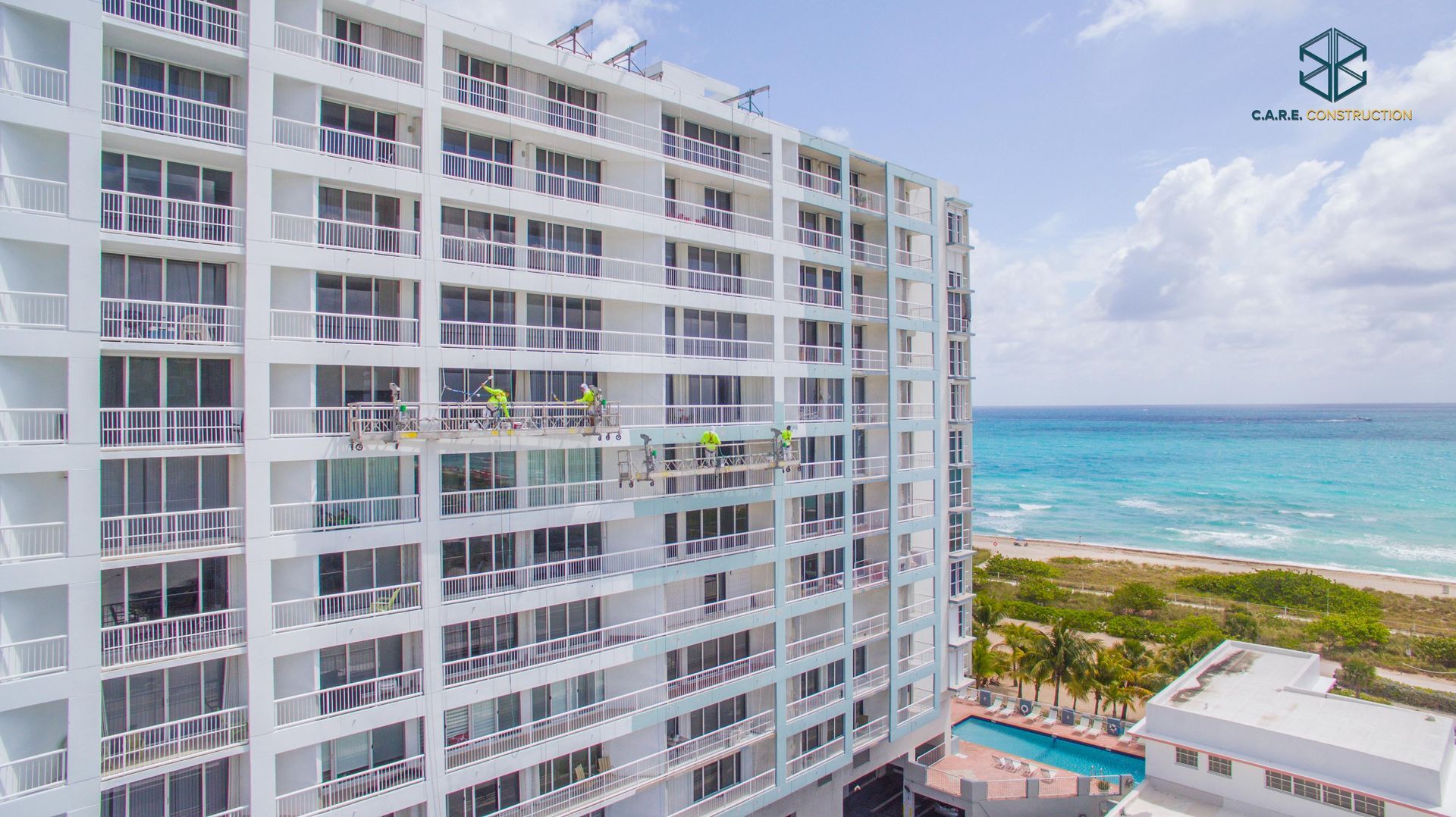 An aerial view of a large white building next to the ocean.