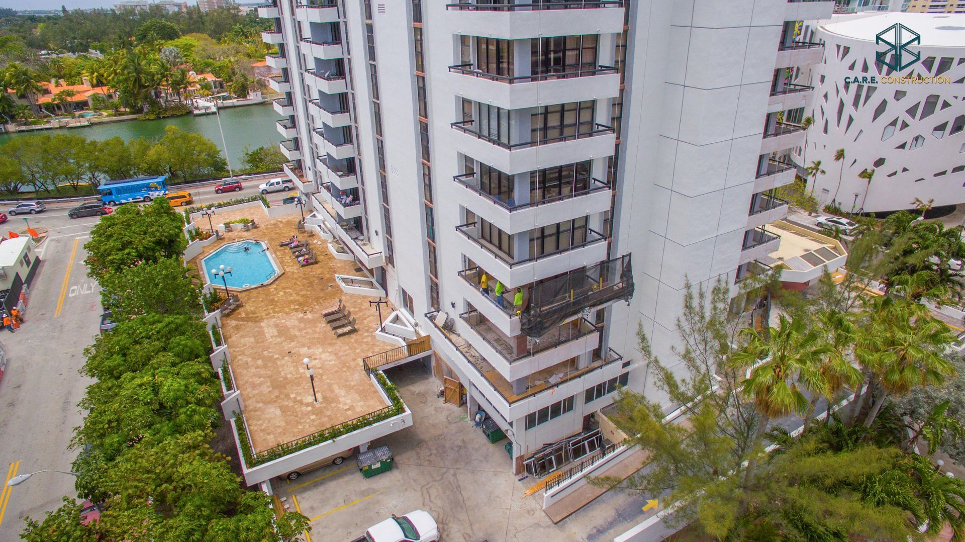 An aerial view of a tall building with a pool in front of it.