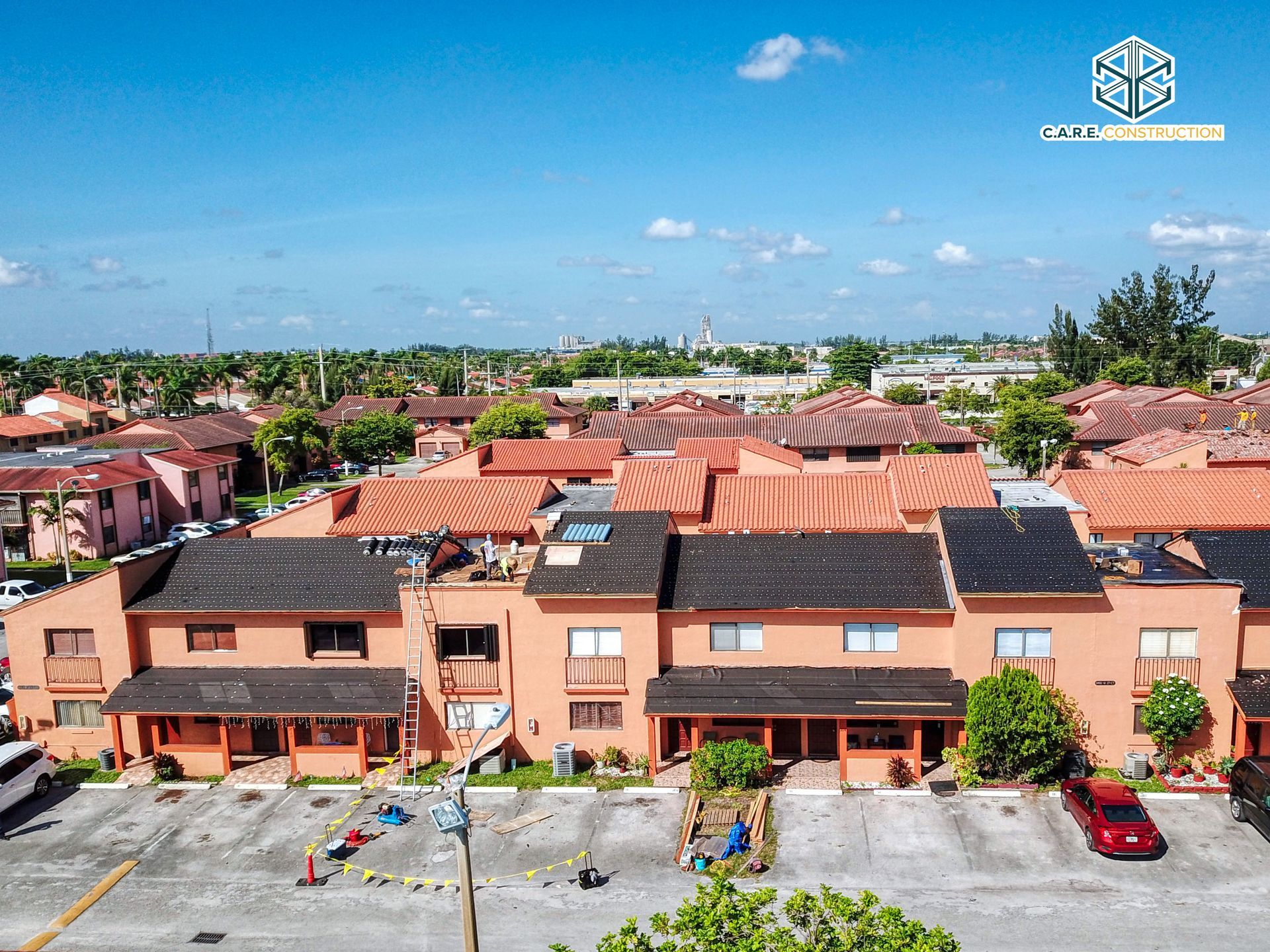 A red car is parked in front of a row of houses