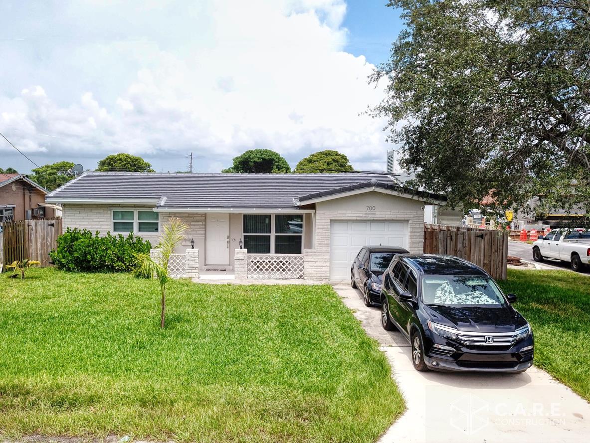 A couple of cars are parked in front of a house.