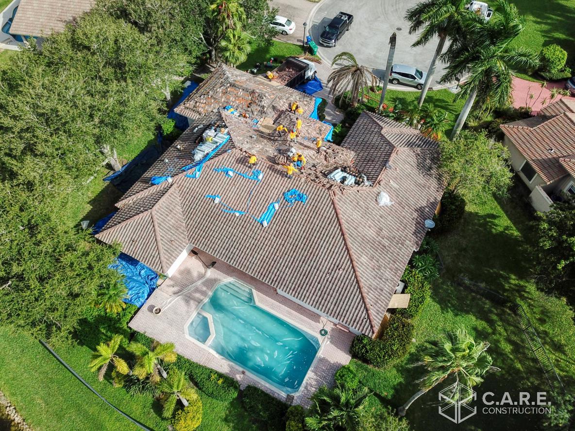 An aerial view of a house with a pool and tarps on the roof.
