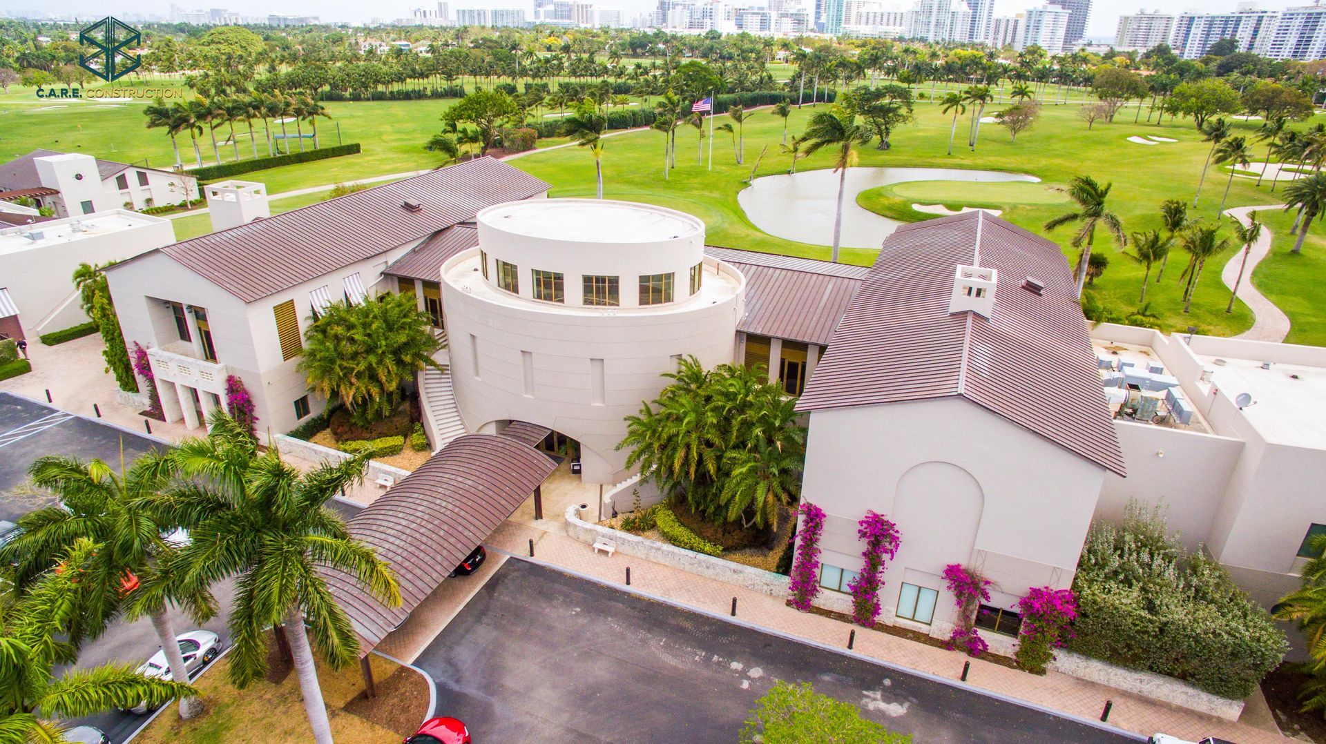An aerial view of a large white building next to a golf course.