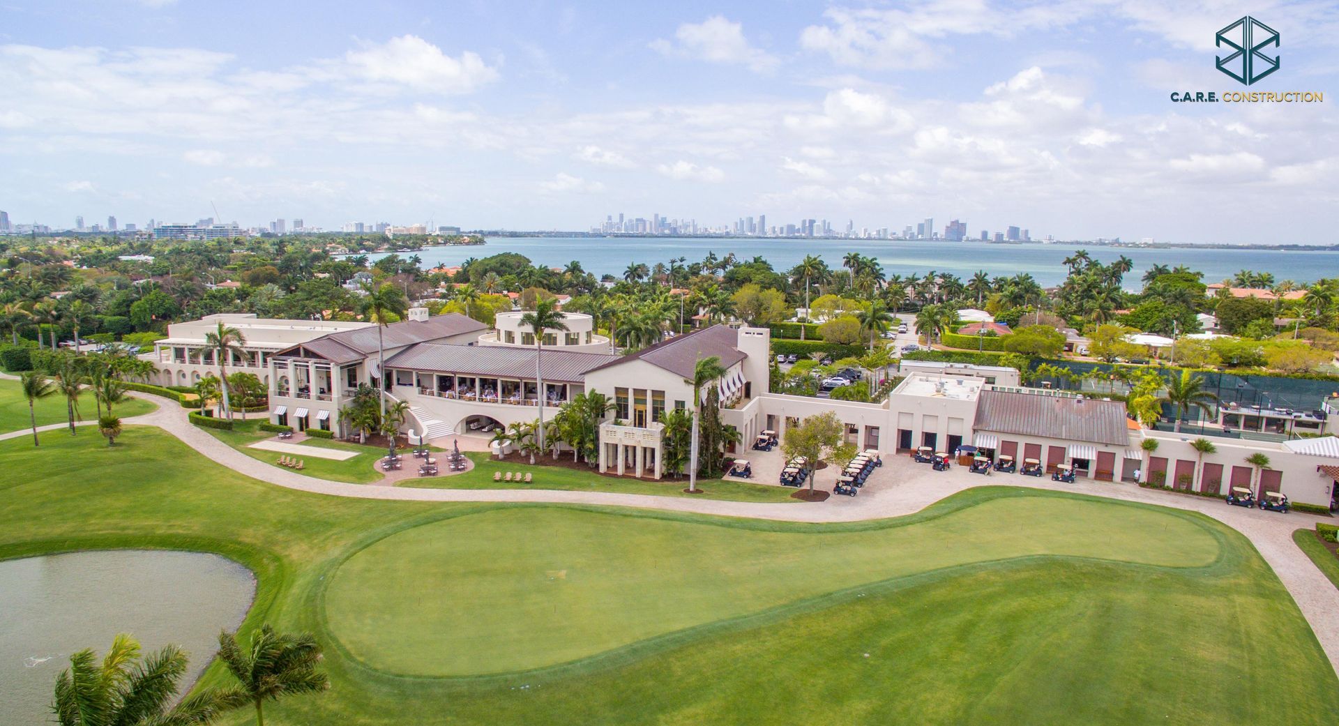 An aerial view of a golf course with a large house in the background.