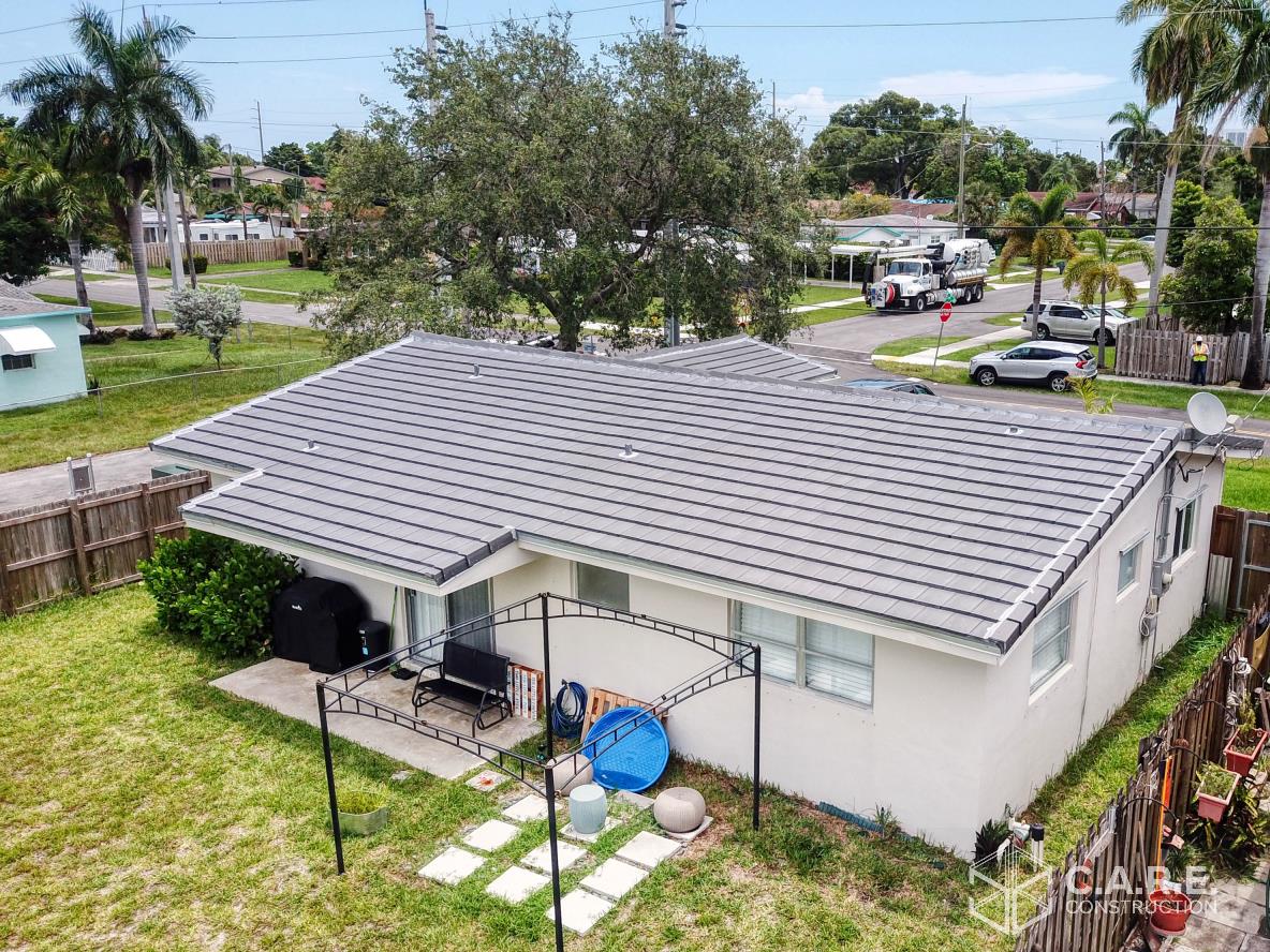 An aerial view of a house with a gray roof in a residential area.