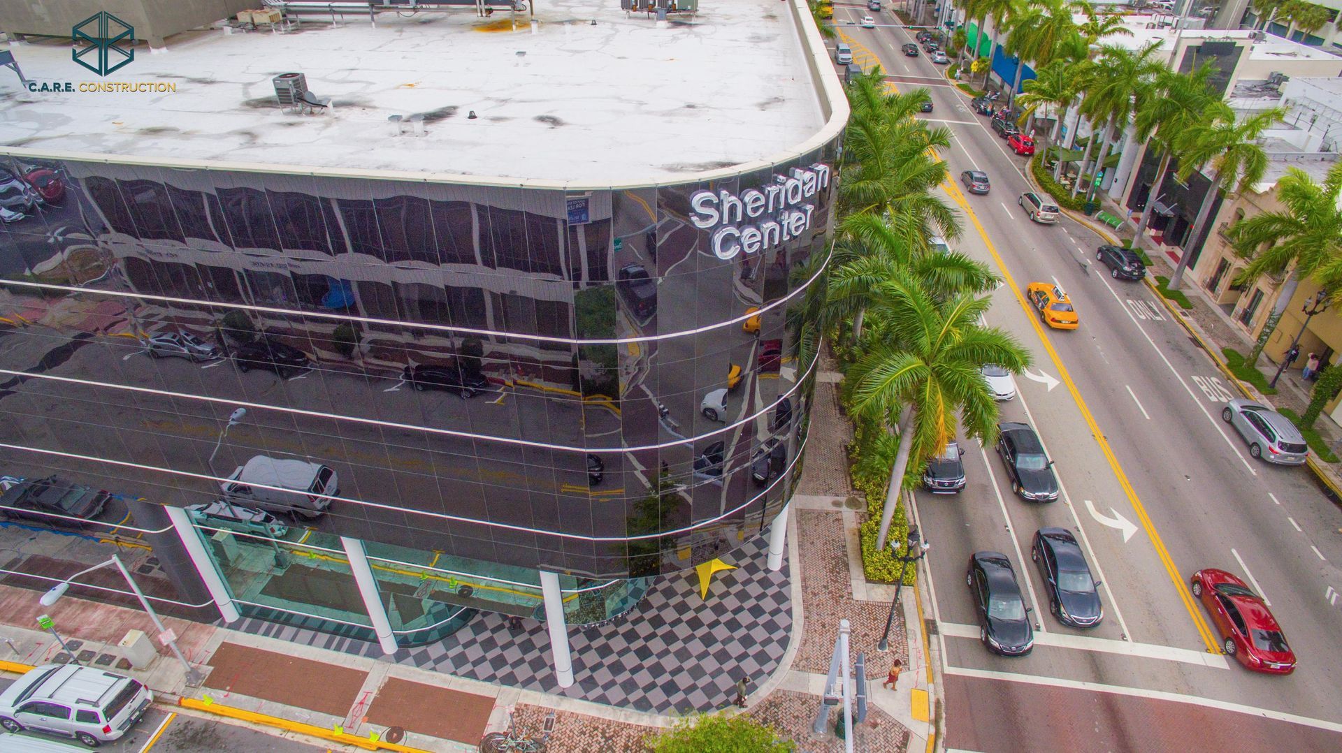 An aerial view of a city street with a building in the middle of it.