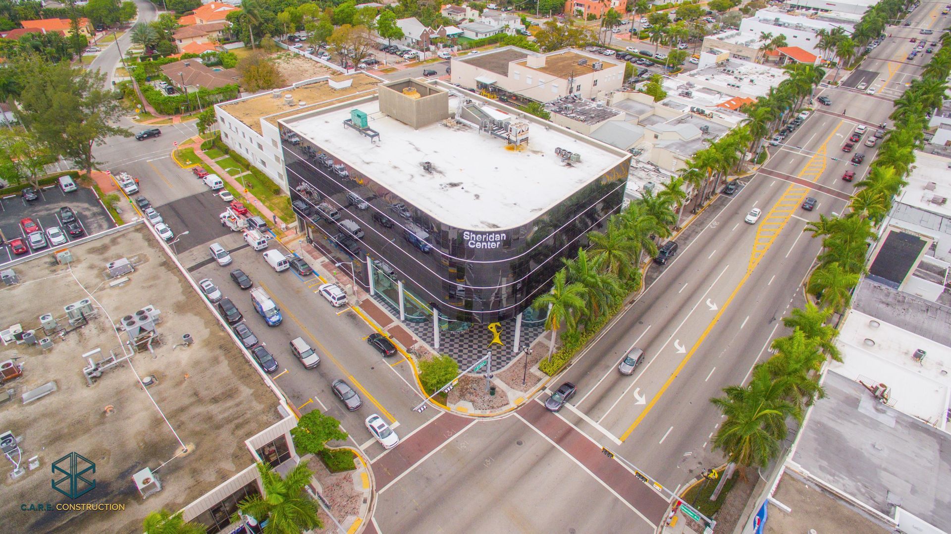 An aerial view of a city with a large building in the middle of the street.