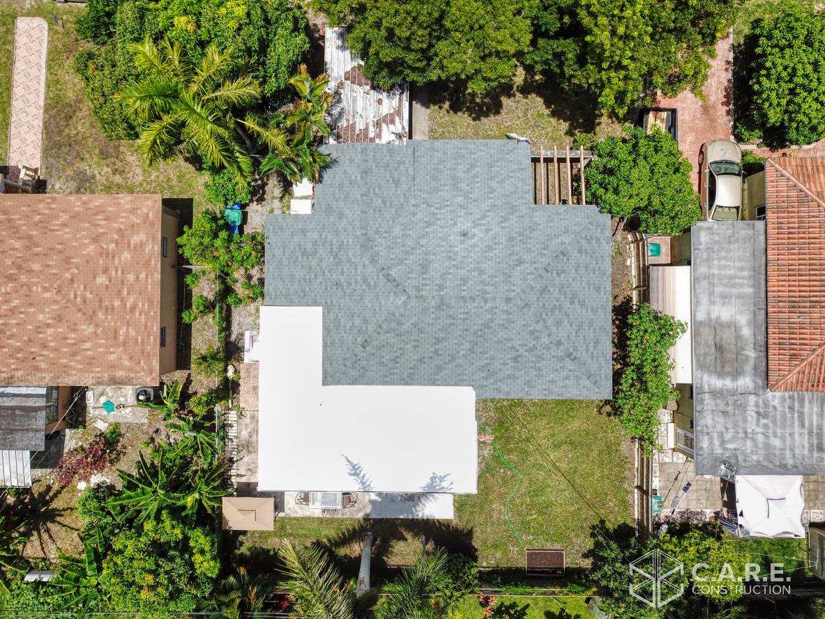 An aerial view of a house with a lot of trees in the backyard.