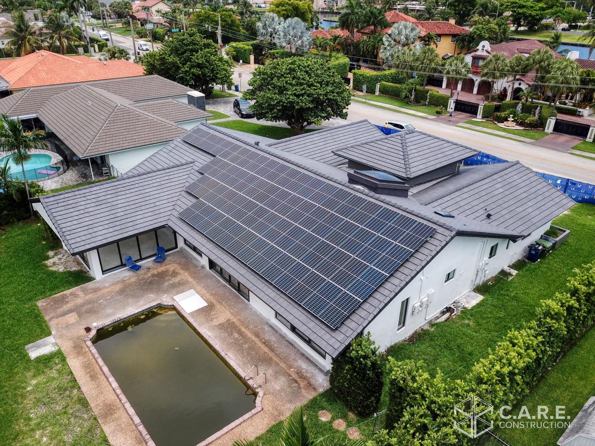 An aerial view of a house with solar panels on the roof and a pool.