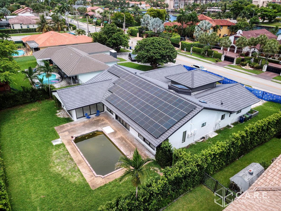 An aerial view of a house with a pool and solar panels on the roof.