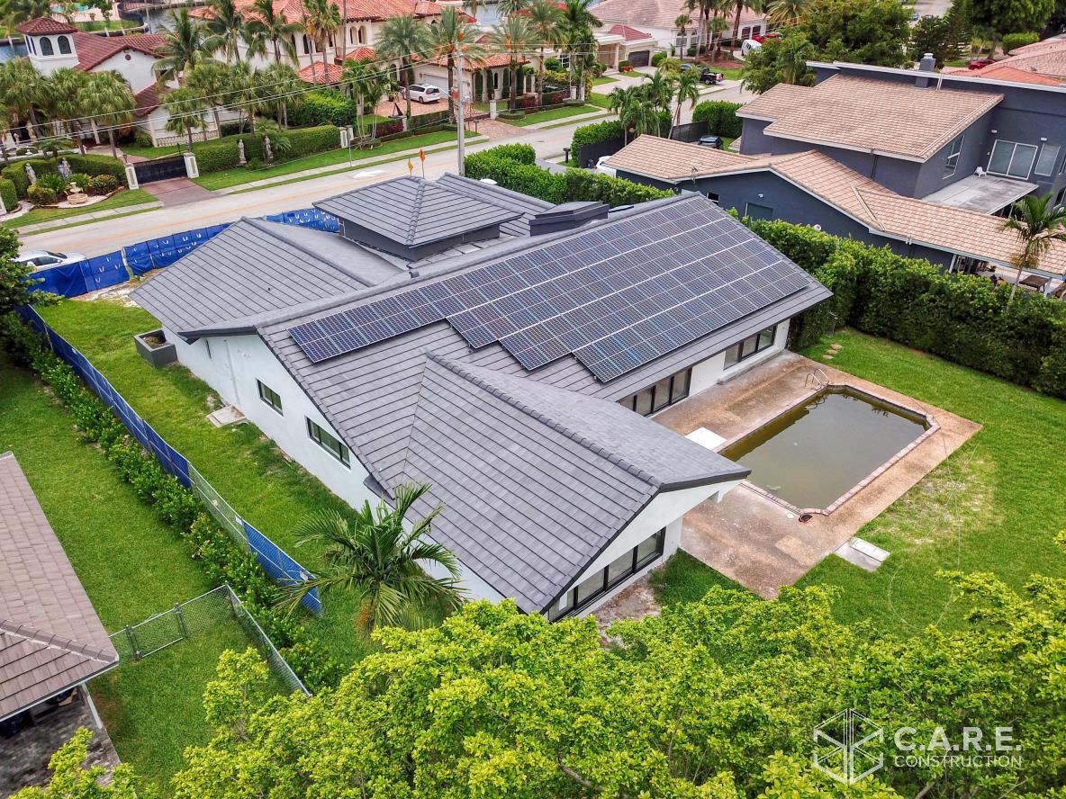 An aerial view of a house with solar panels on the roof and a pool.