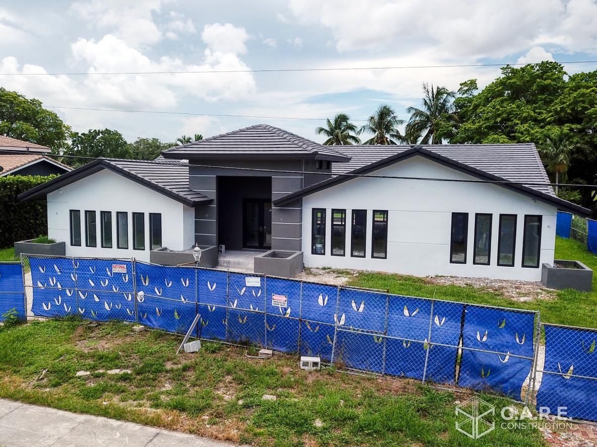 A house that is being built with a lot of blue tarps in front of it.