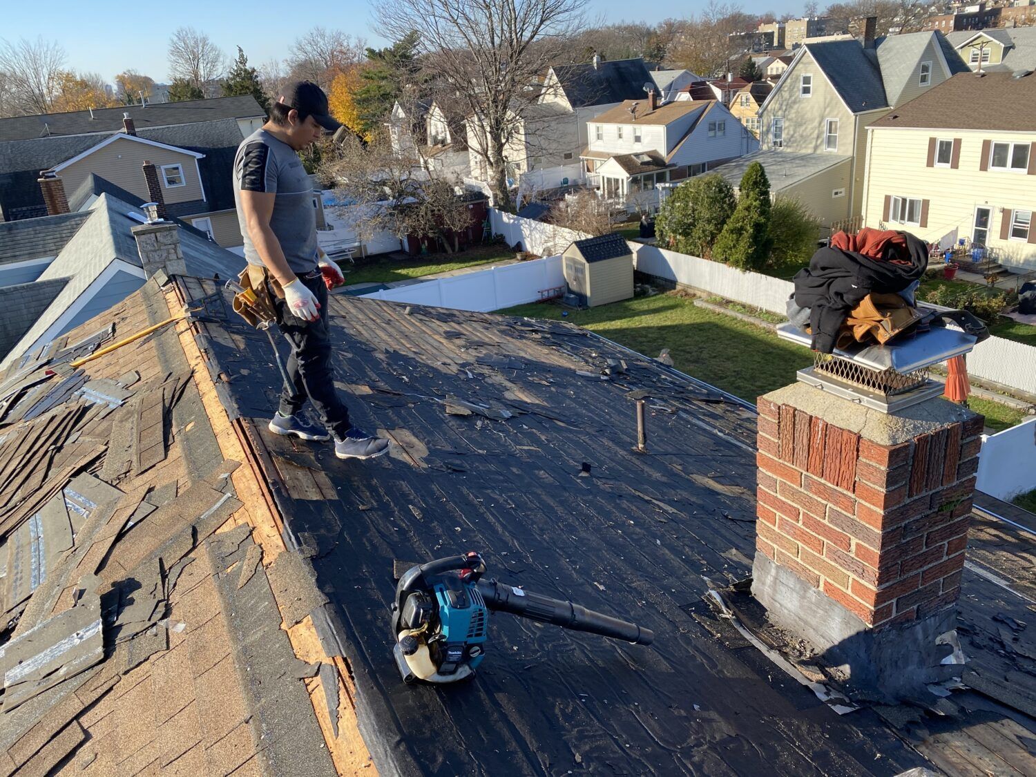 A man is standing on top of a roof with a vacuum cleaner.