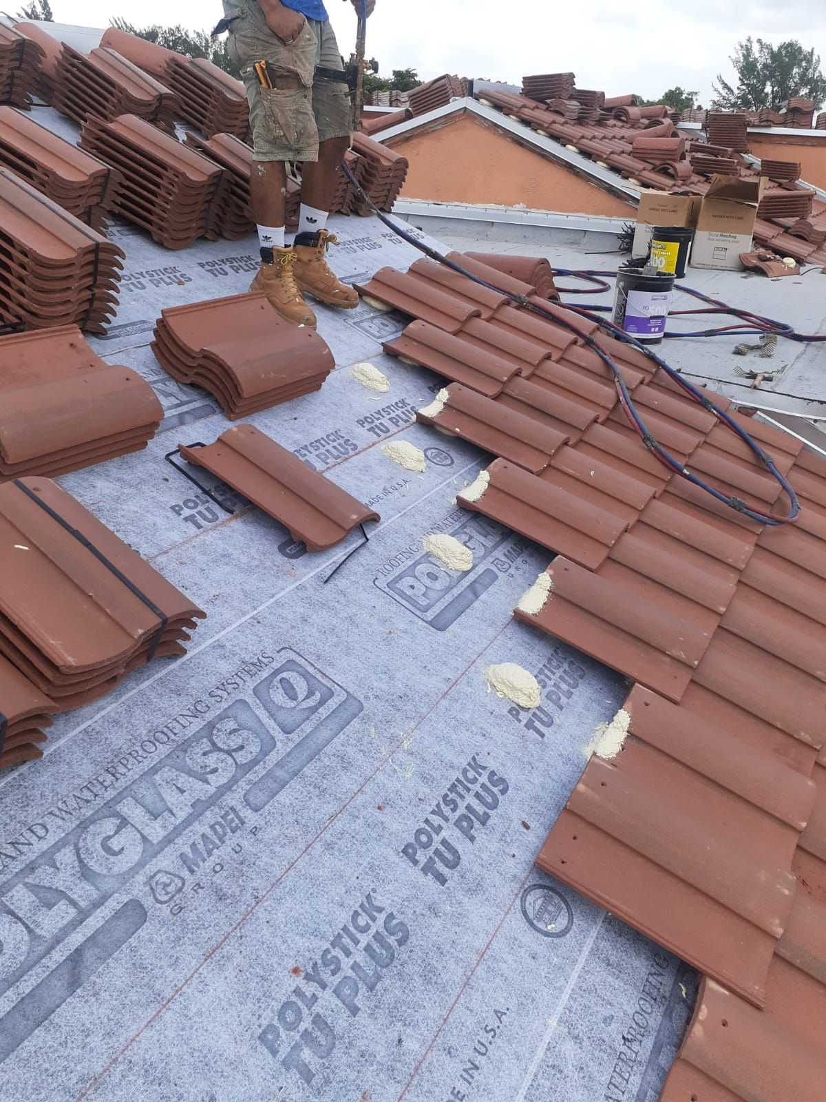 A man is standing on top of a roof covered in tiles.