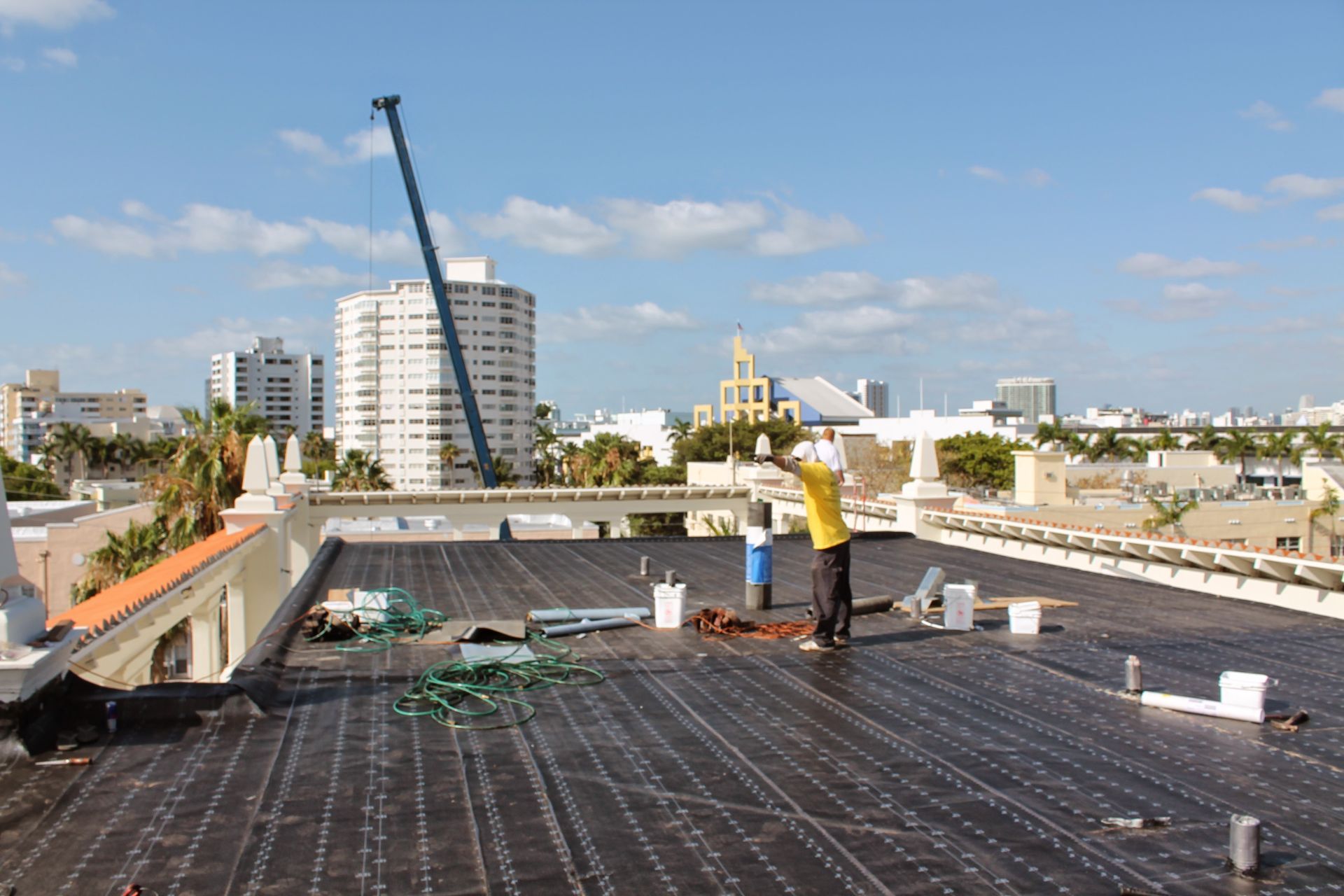 A man is standing on the roof of a building with a crane in the background.