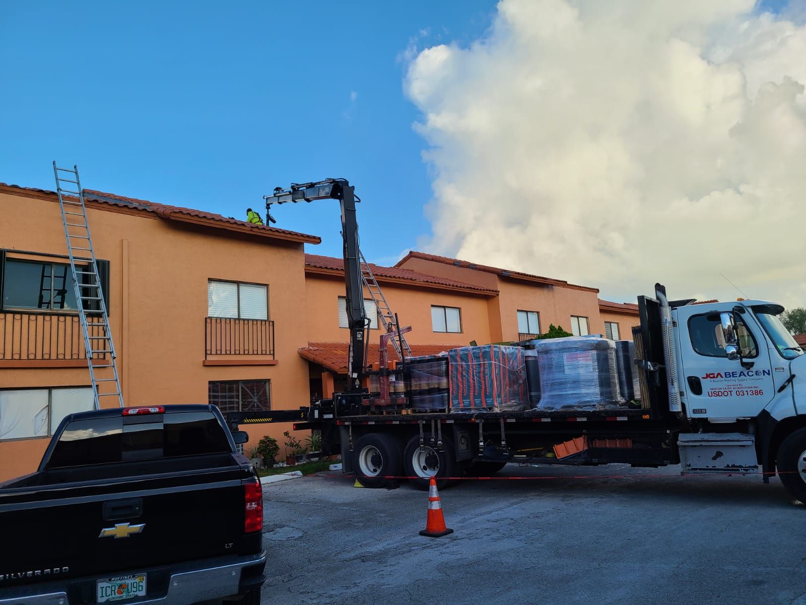 A truck with a crane on the back is parked in front of a building