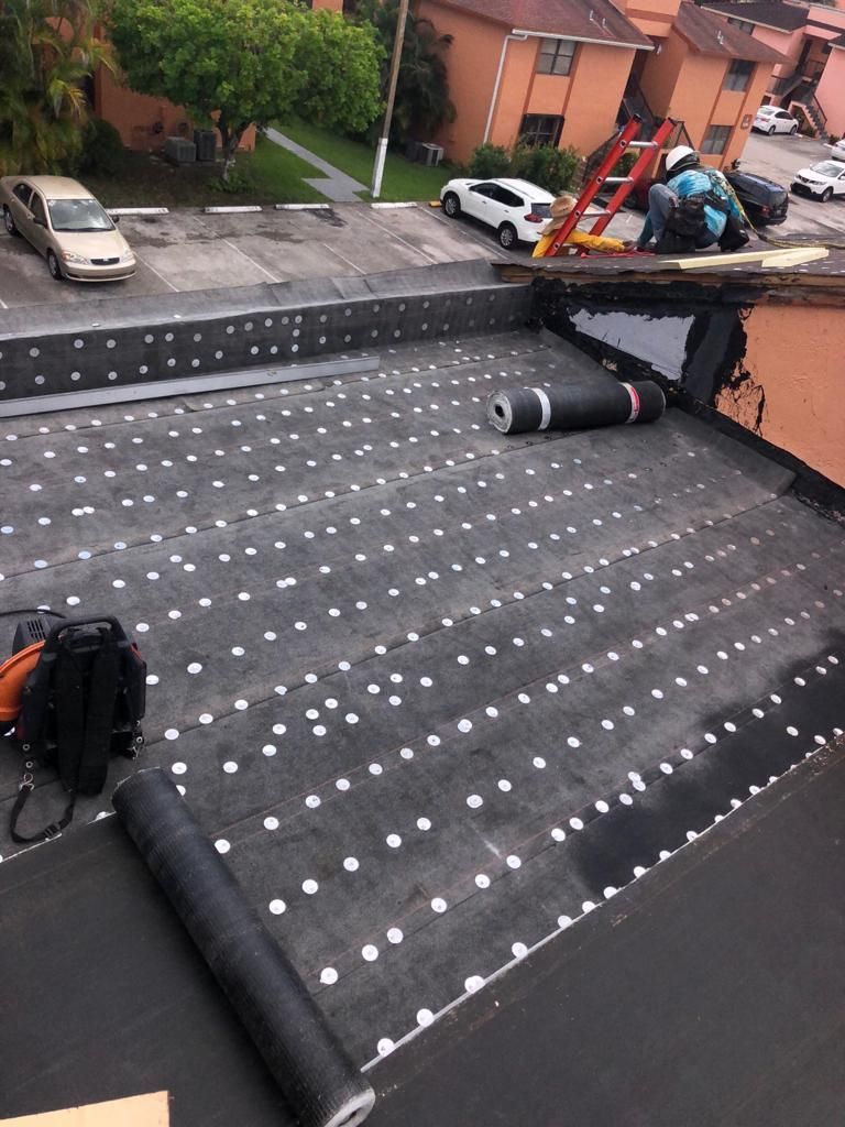 A black roof with white dots is being installed on a building.