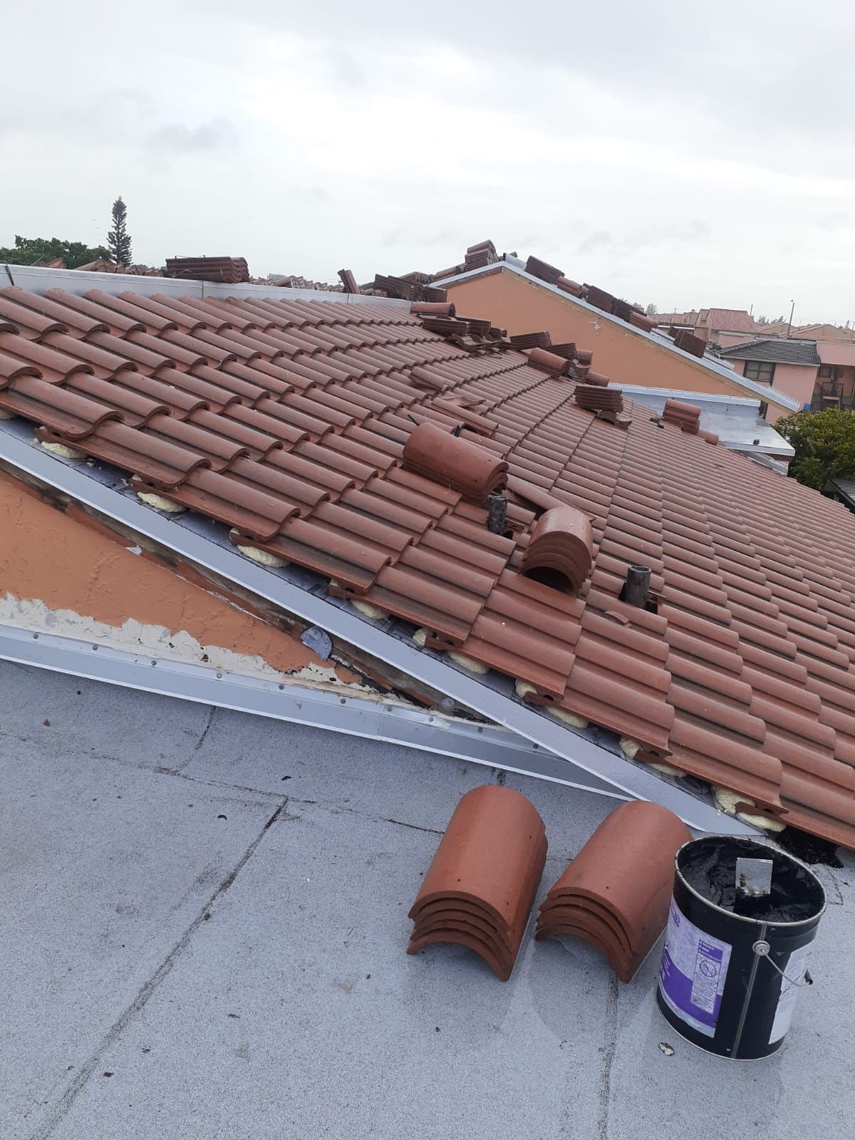 A roof with a lot of tiles and a bucket of paint on it.
