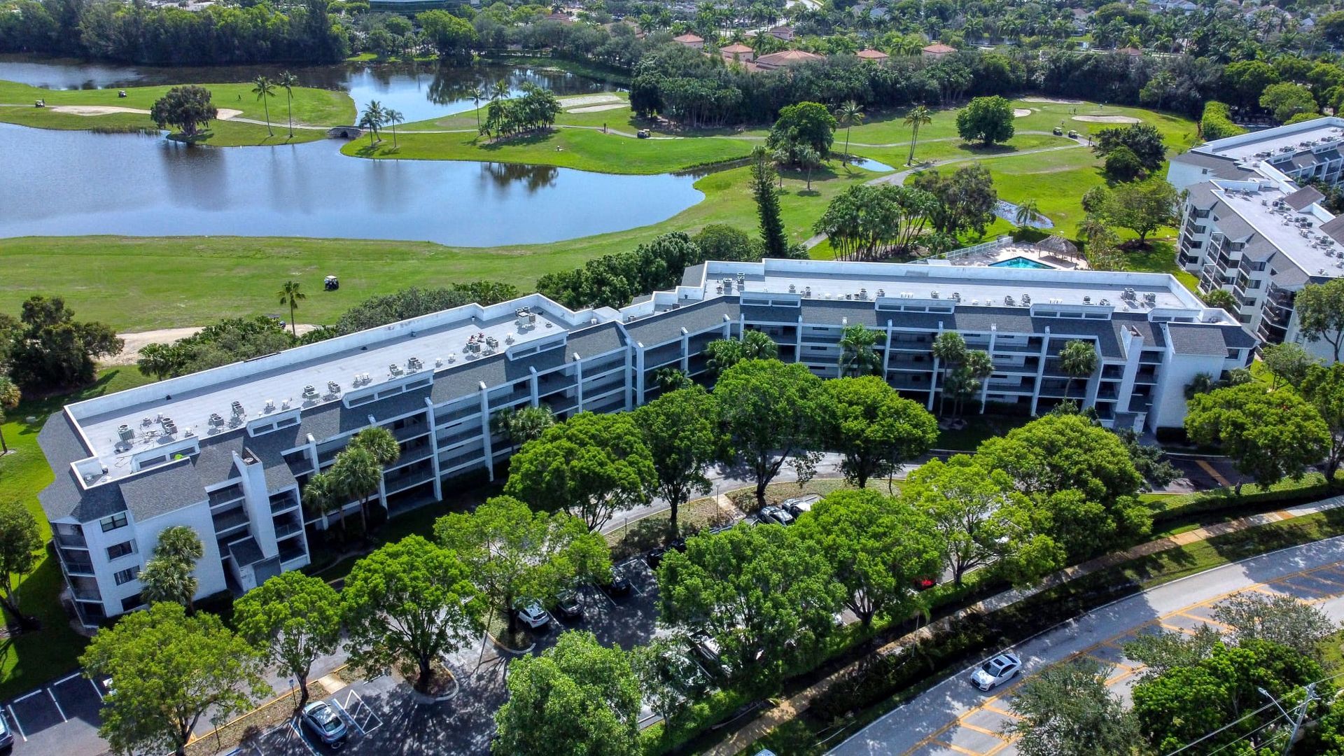 An aerial view of a large building surrounded by trees and a lake