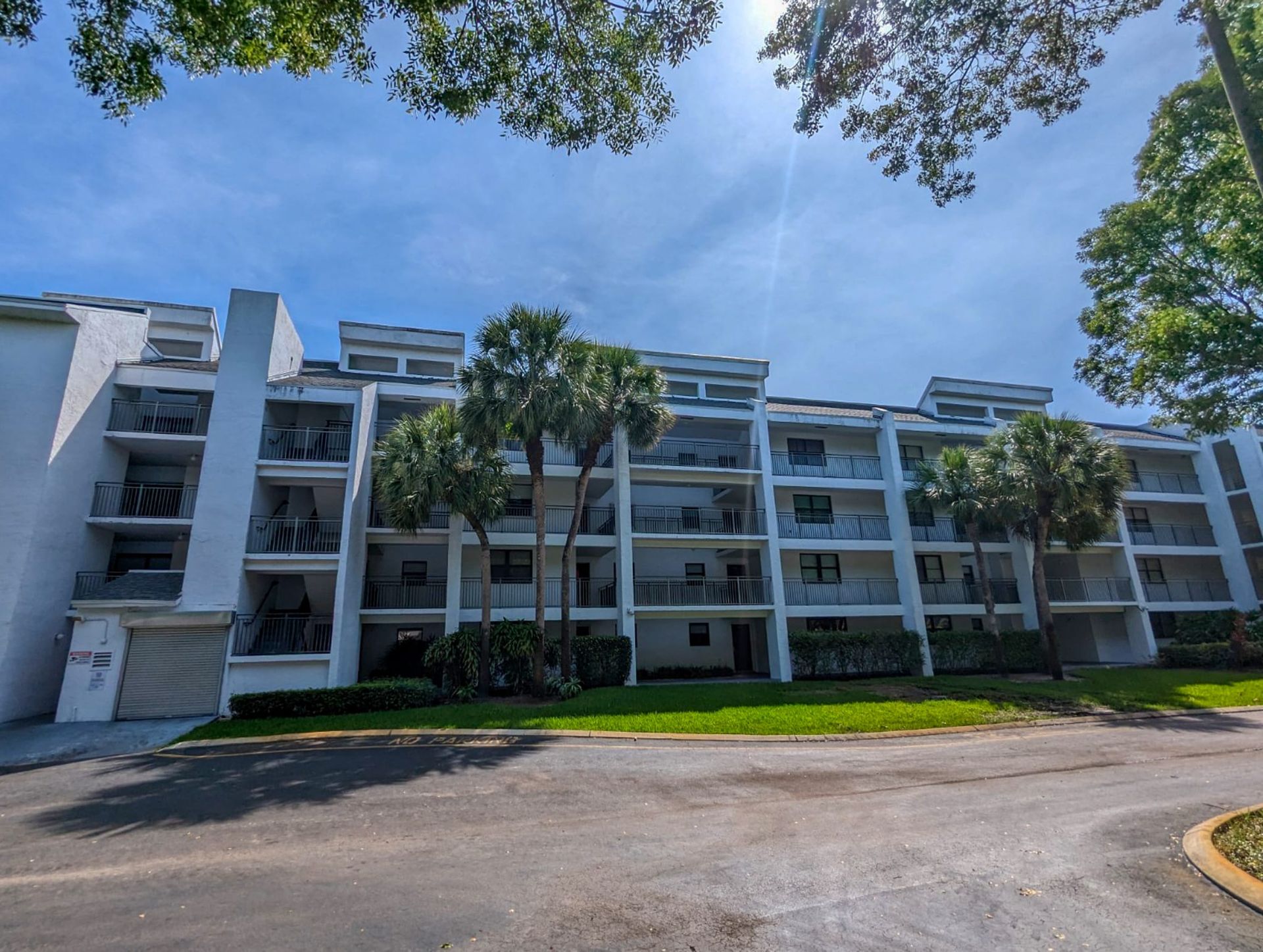 A large white apartment building with palm trees in front of it