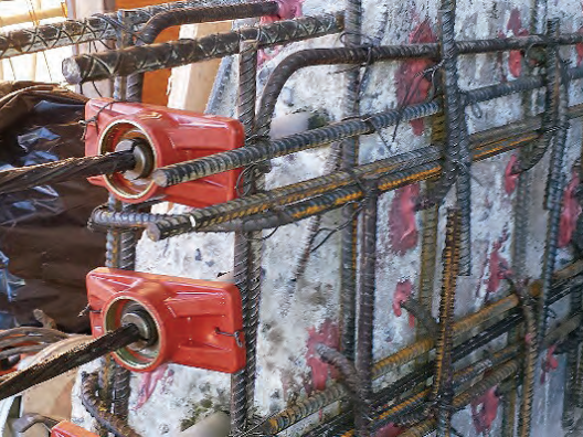 A close up of a metal structure with a concrete wall in the background.