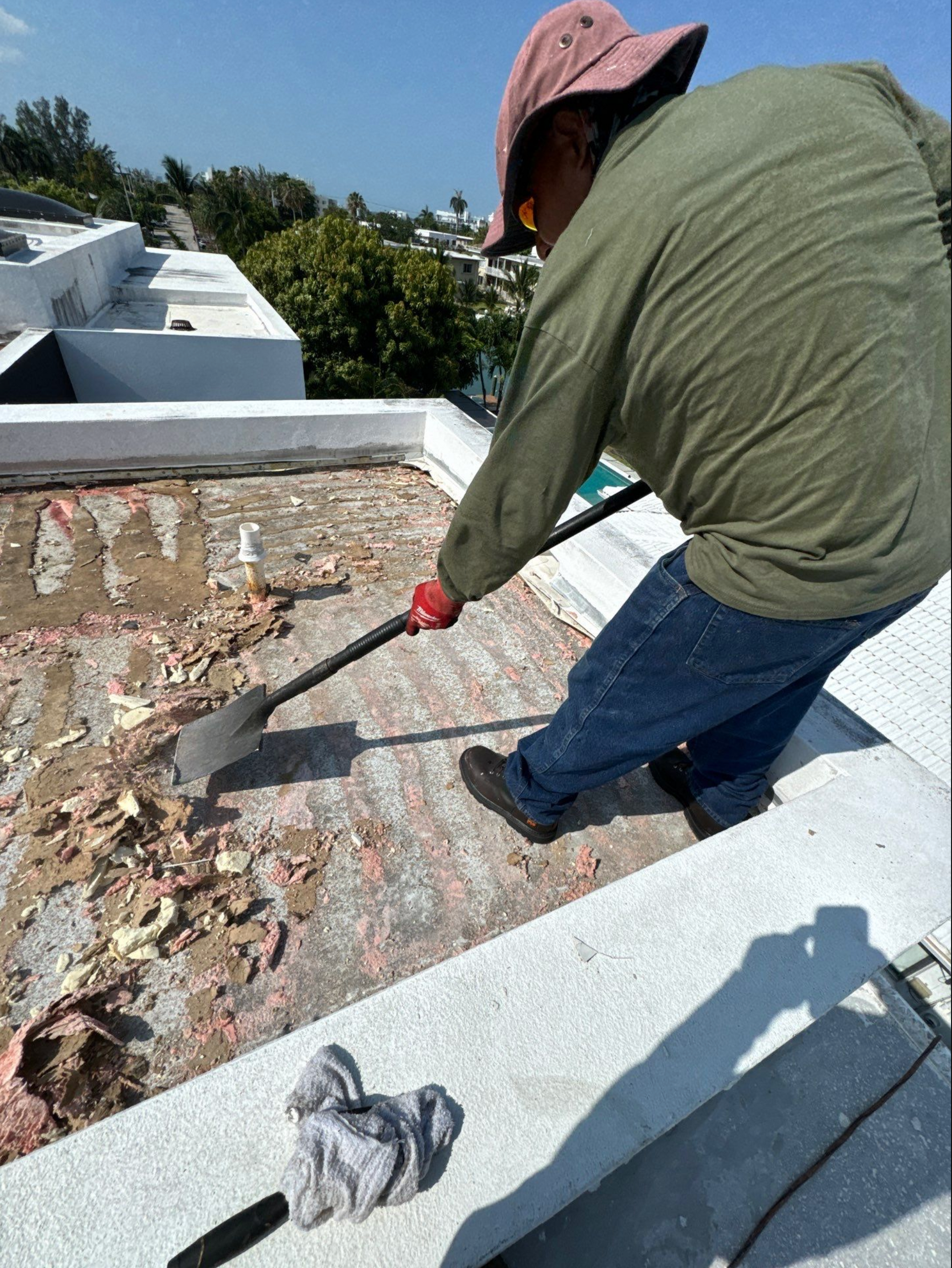 A man is working on the roof of a building with a shovel.