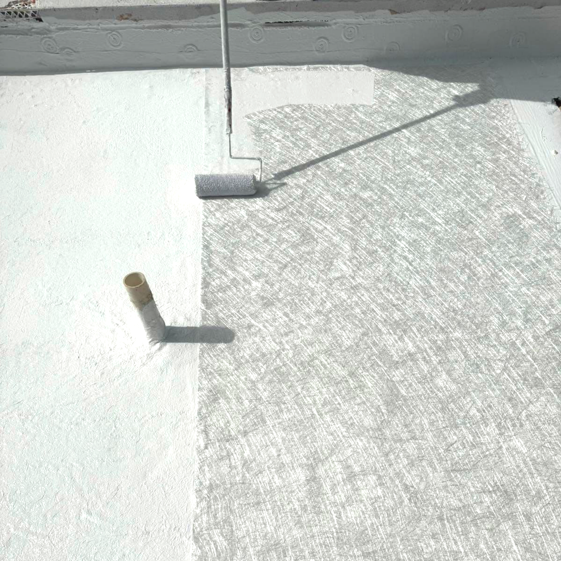 A person is painting a roof with a roller.