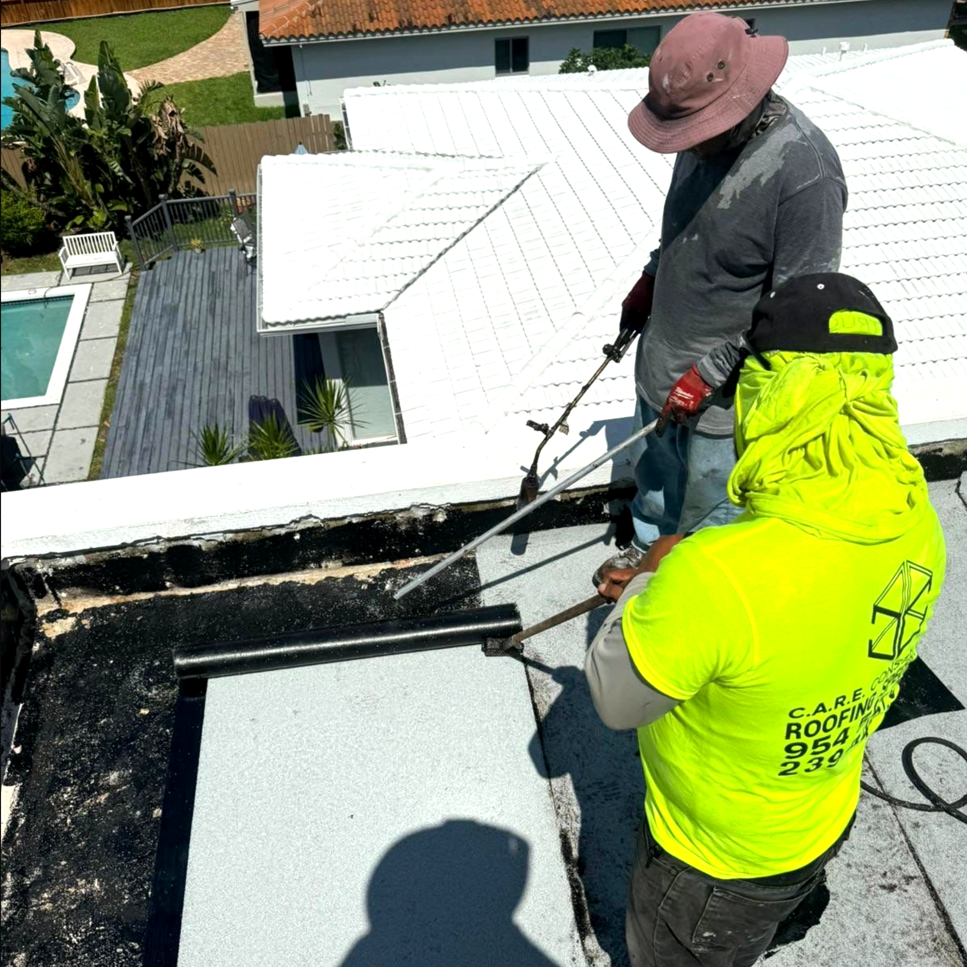 Two men are working on the roof of a house