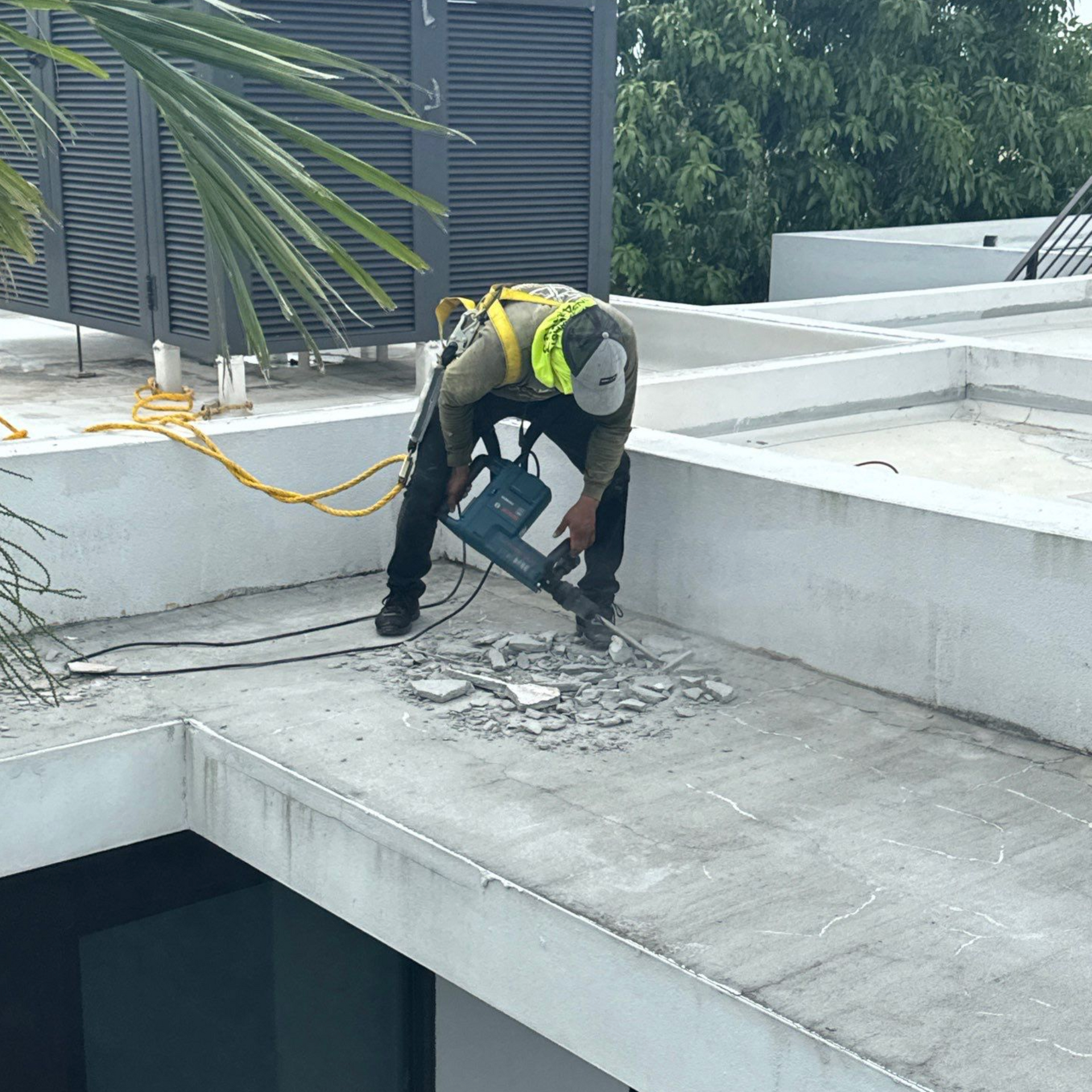 A man is working on the roof of a building with a hammer.