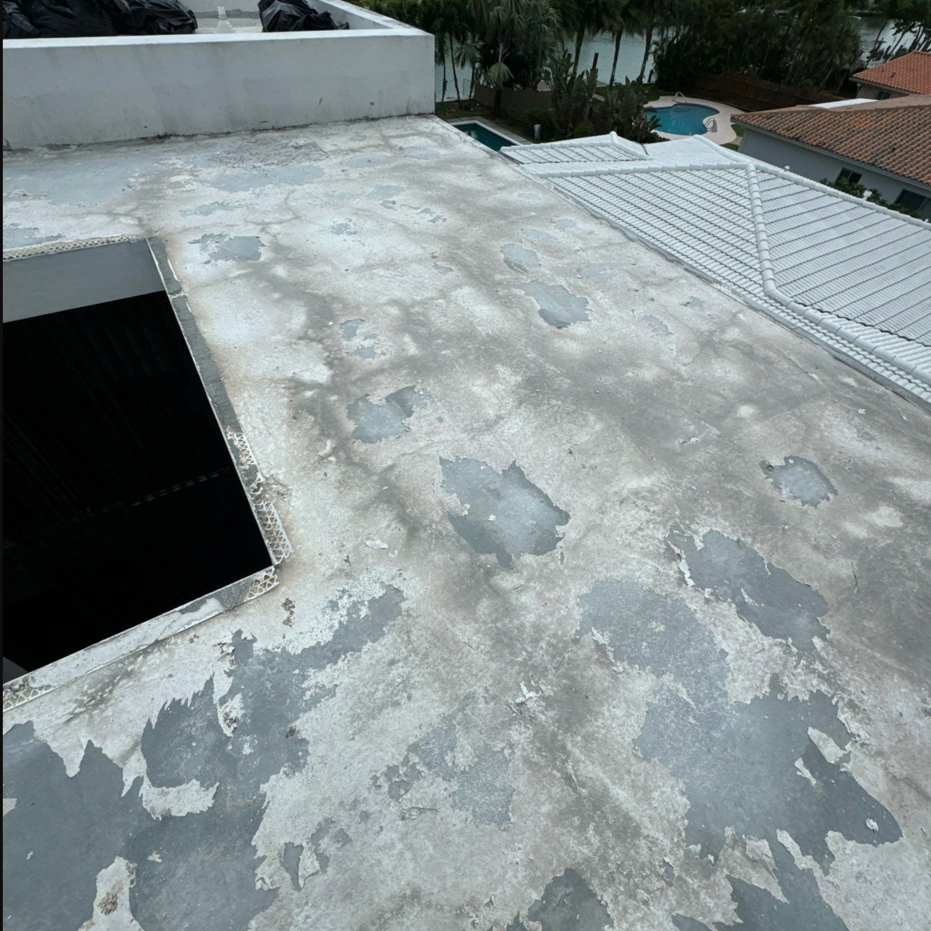 A roof with a hole in it and a pool in the background