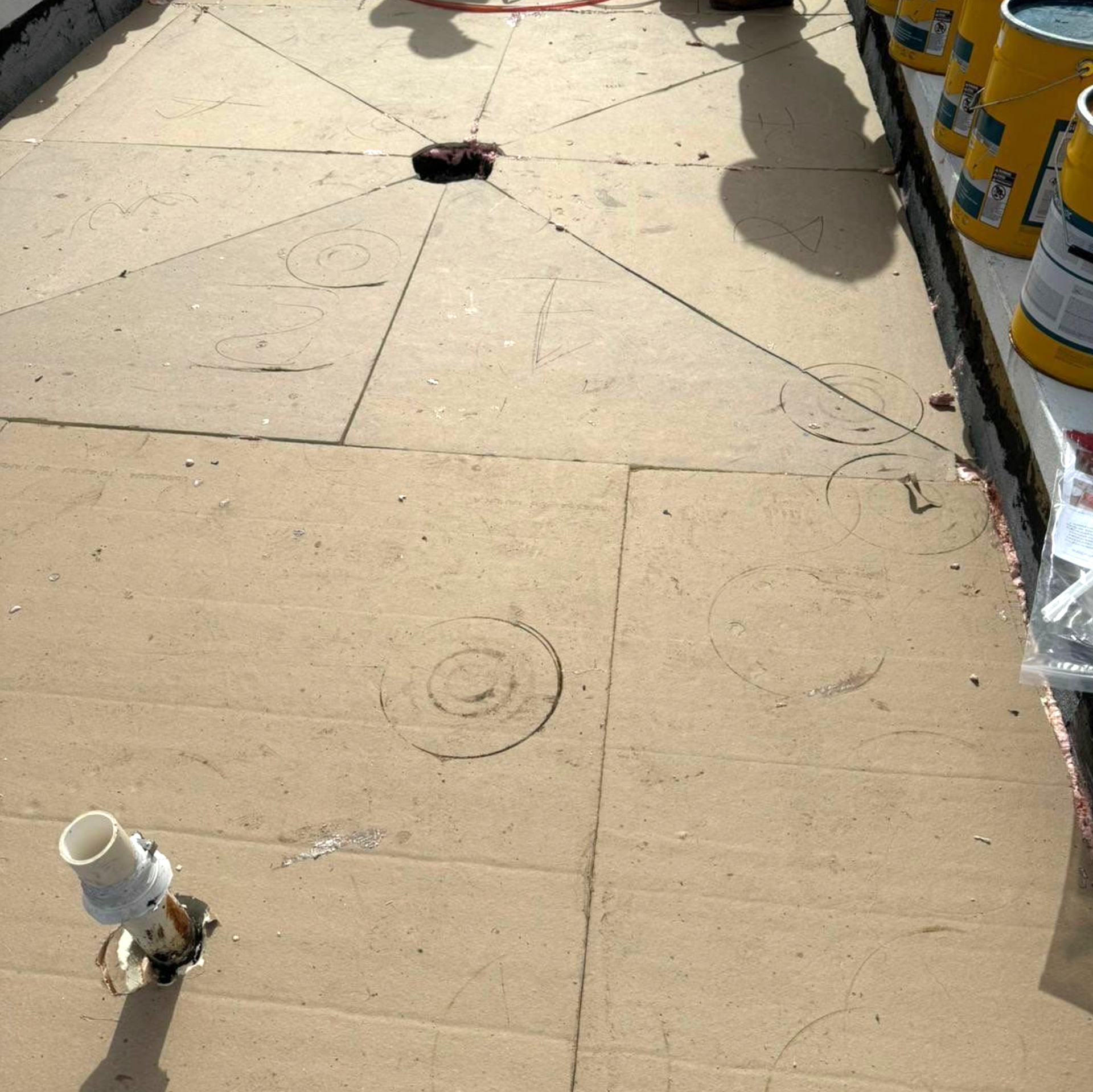 Buckets of paint are lined up on a cardboard floor