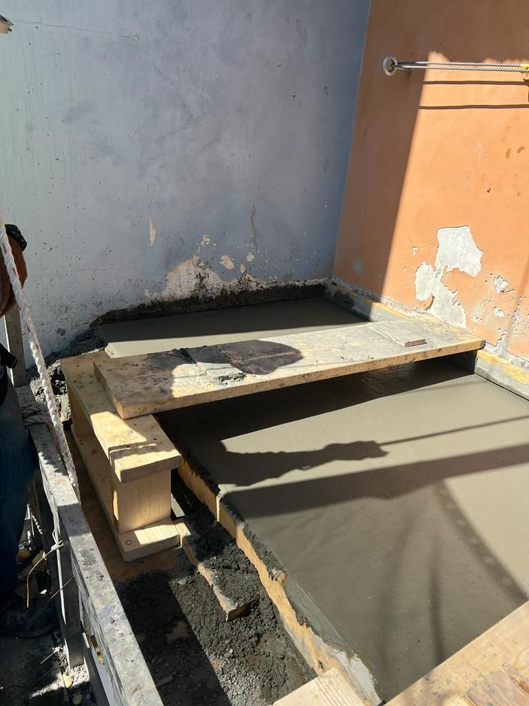 A man is laying concrete on top of a wooden platform.
