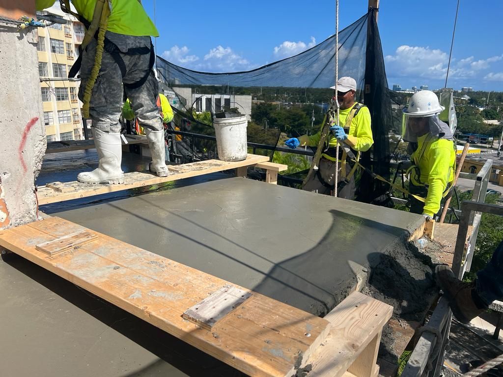 A group of construction workers are working on a concrete floor.