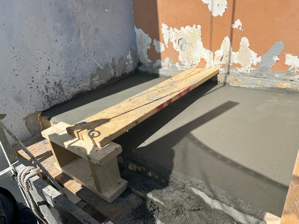 A wooden bench is sitting on top of a concrete floor.