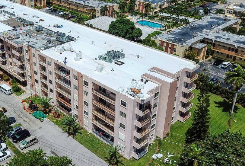 An aerial view of a large apartment building with a white roof